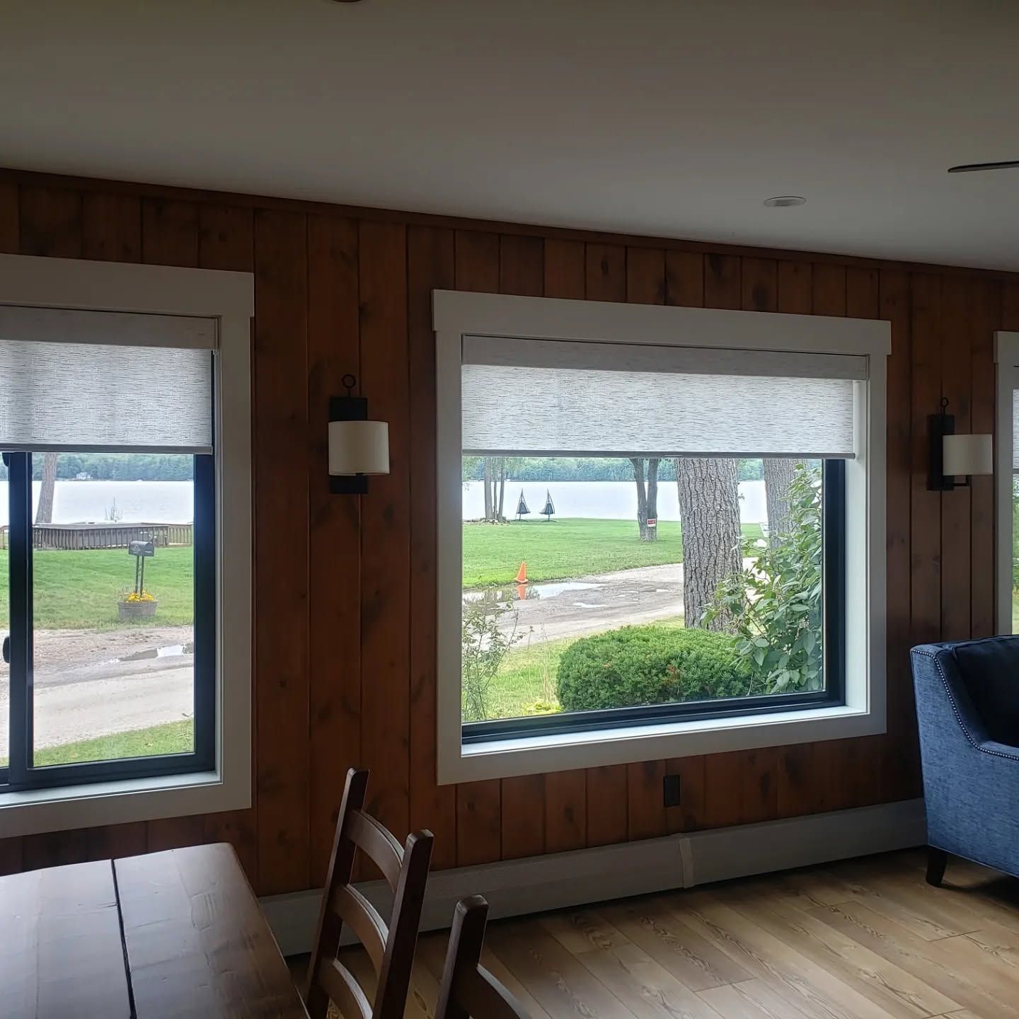 Wood-paneled room with two large windows looking out onto a lawn and road