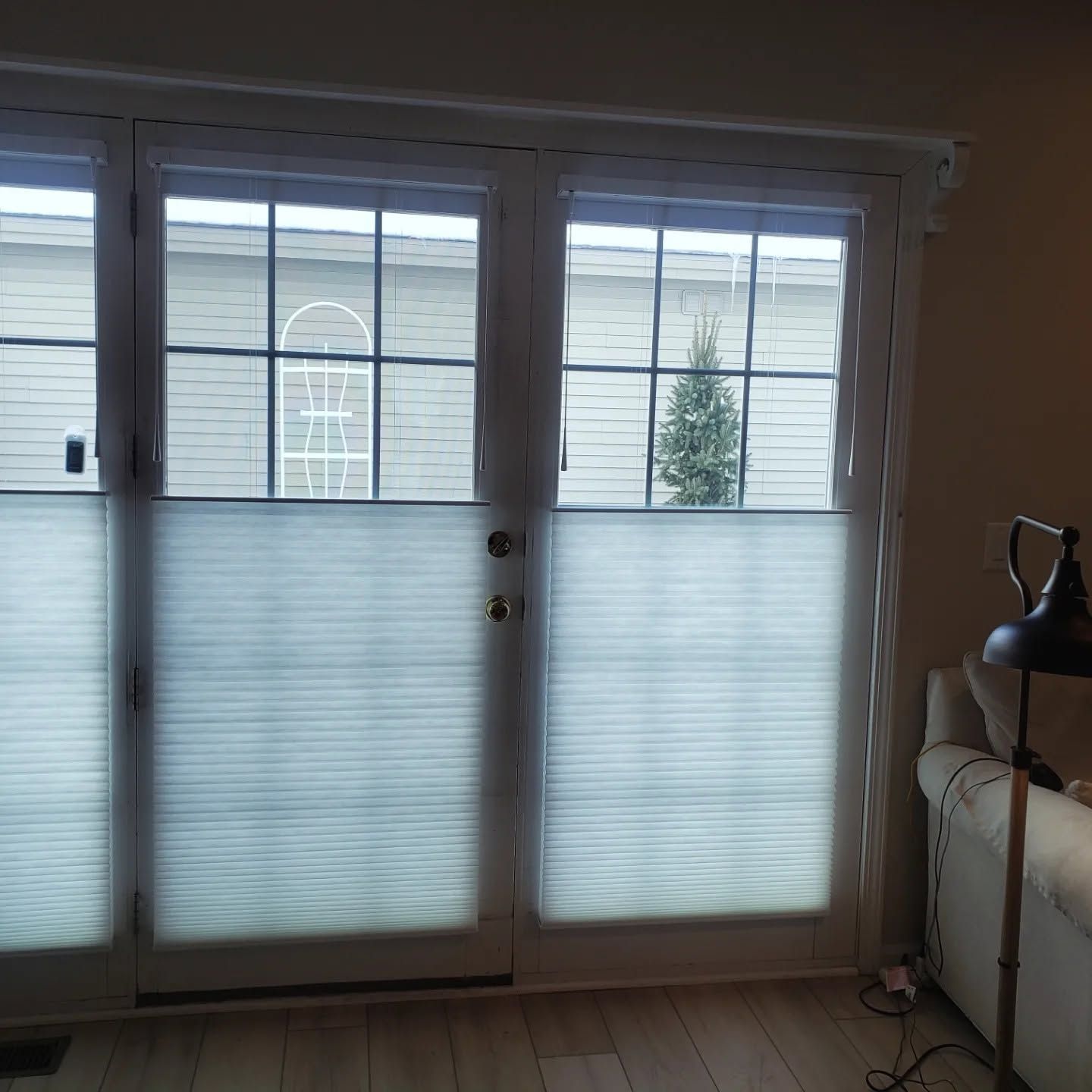 Sliding glass doors with frosted lower panels and curtains, looking out onto a balcony and trees.