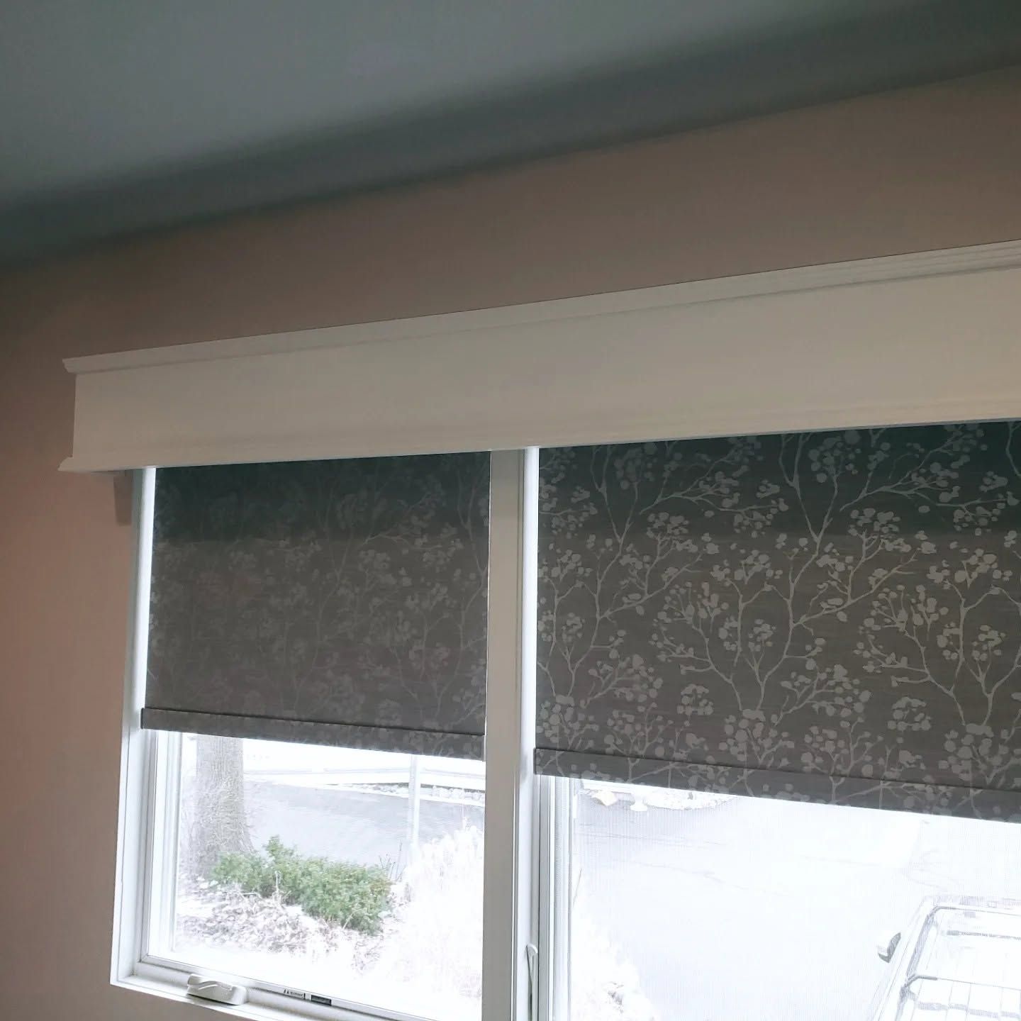 Two small dark floral blinds cover windows in a softly lit room