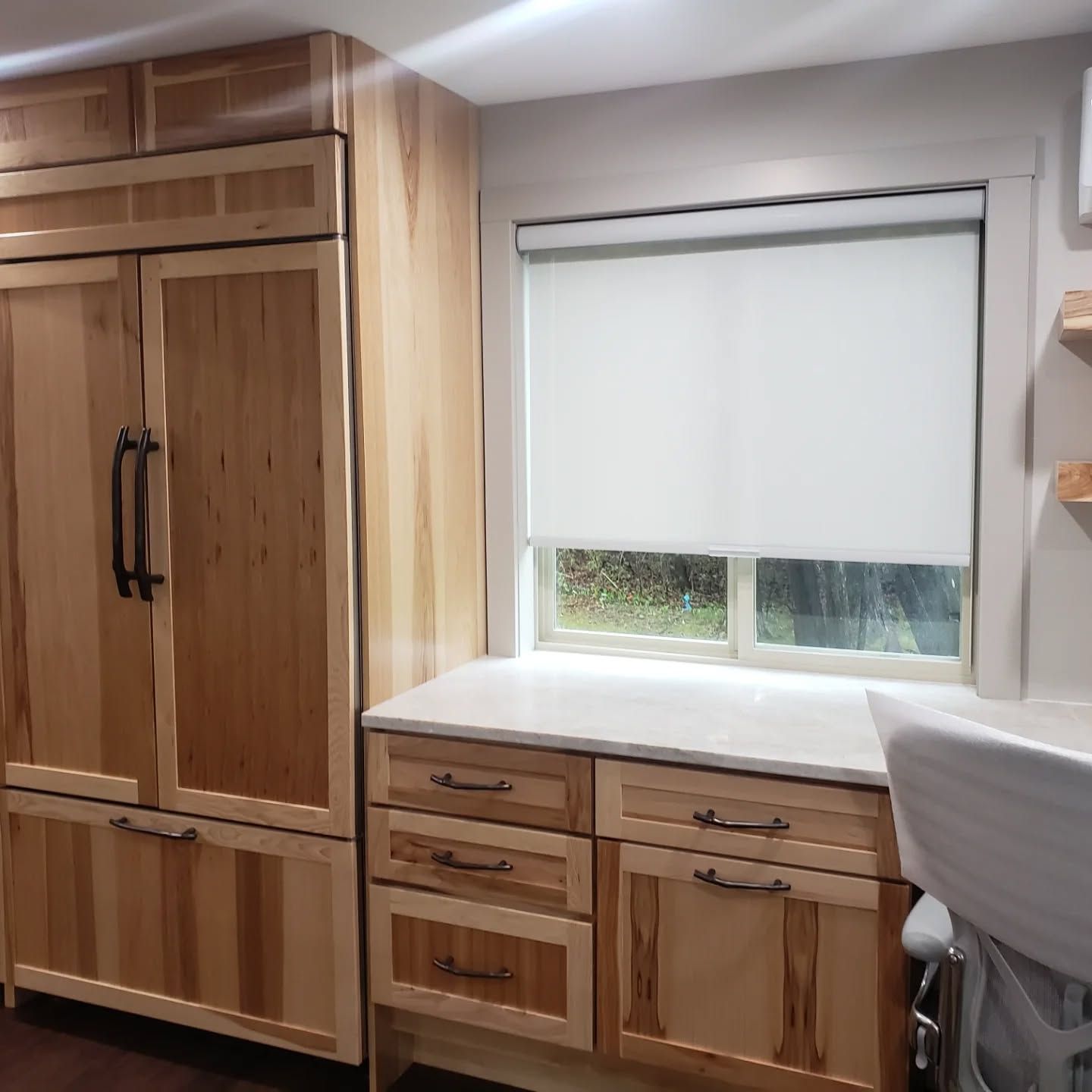 Wood-paneled kitchen with built-in cabinets, drawers, and a window above the countertop.