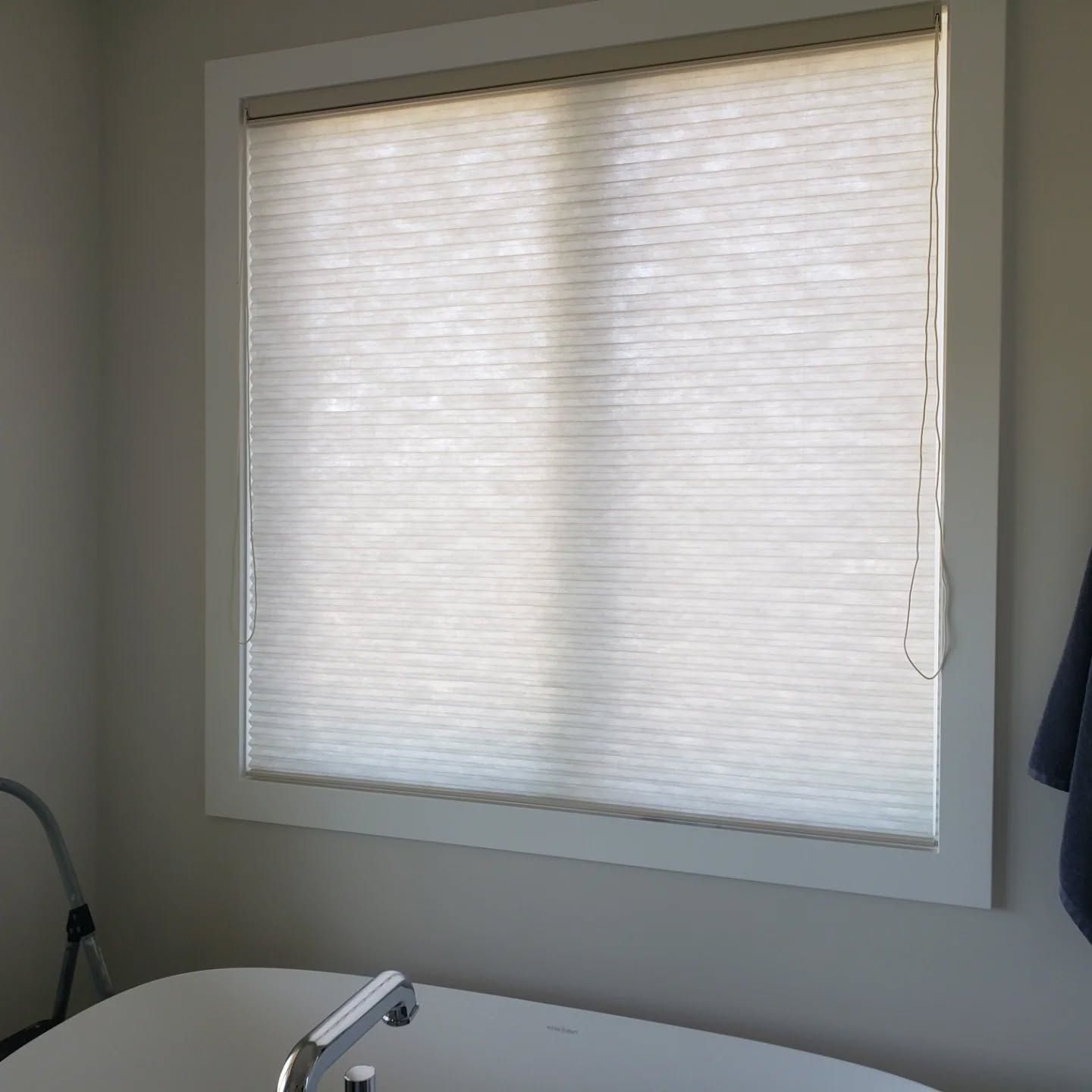 White window blind in a gray-walled room above a sink faucet