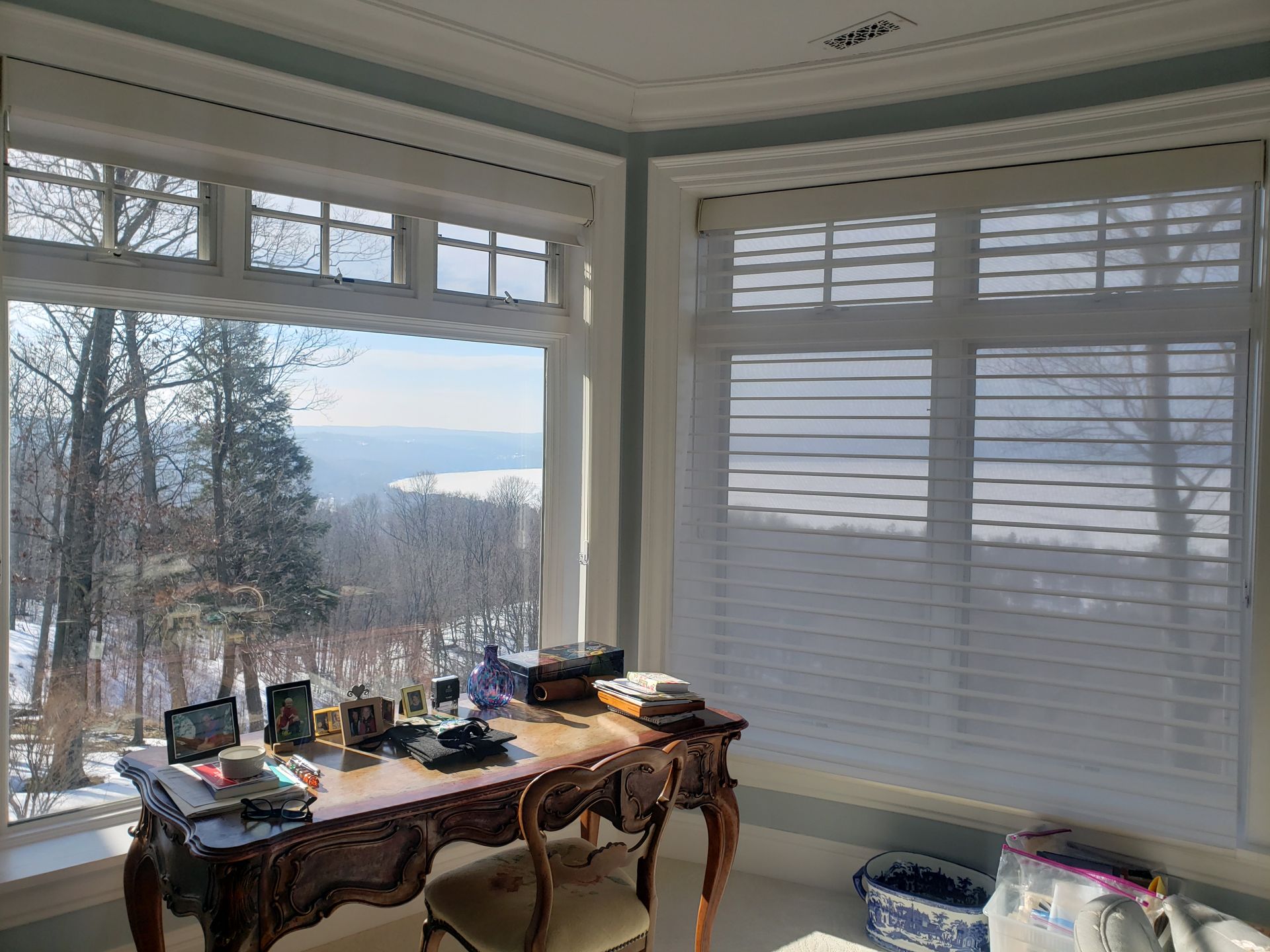 Bright sunroom with a wooden desk by large windows, overlooking a snowy landscape.