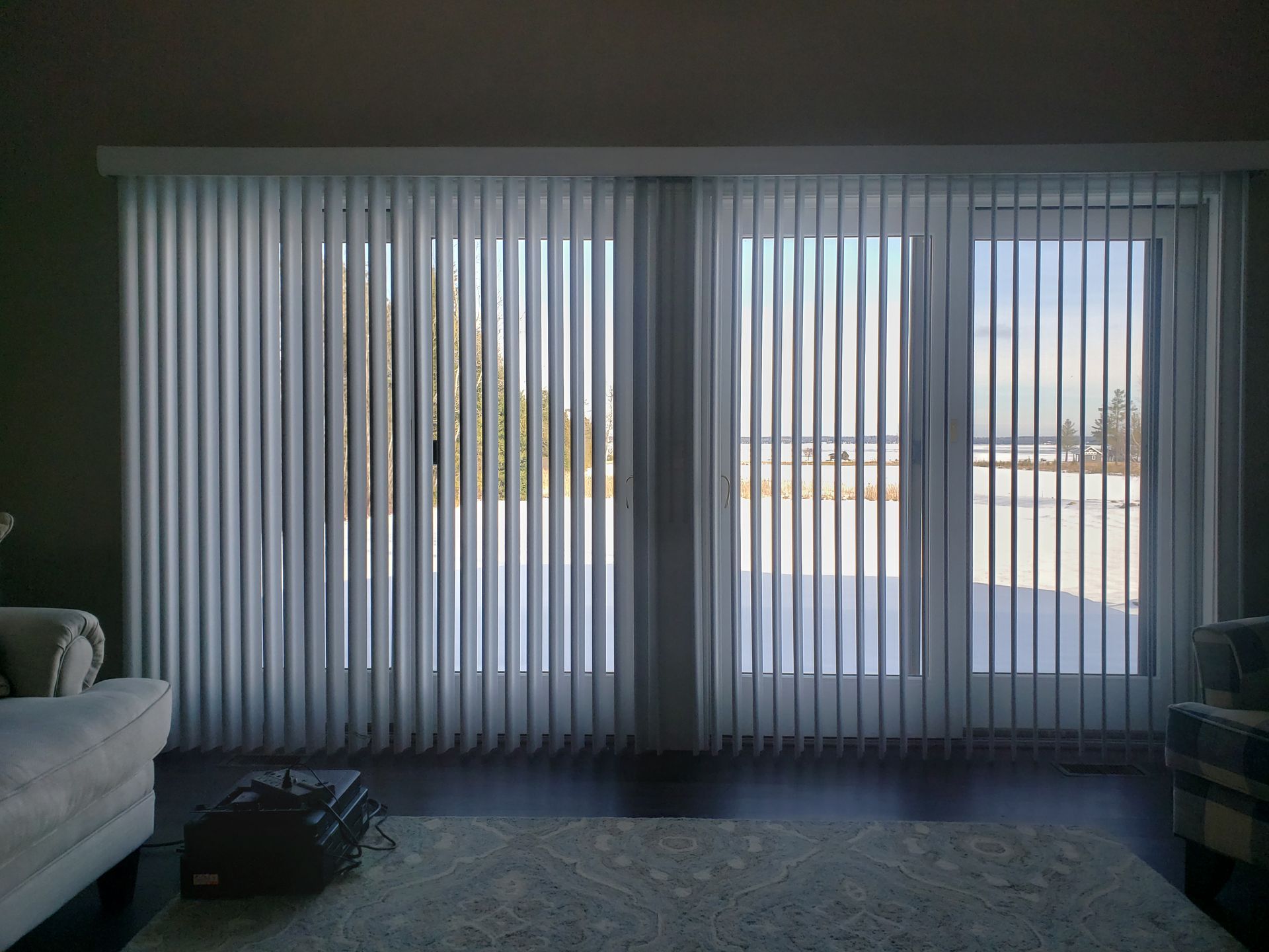 Living room with vertical blinds covering large sliding glass doors, bright outdoor light visible.