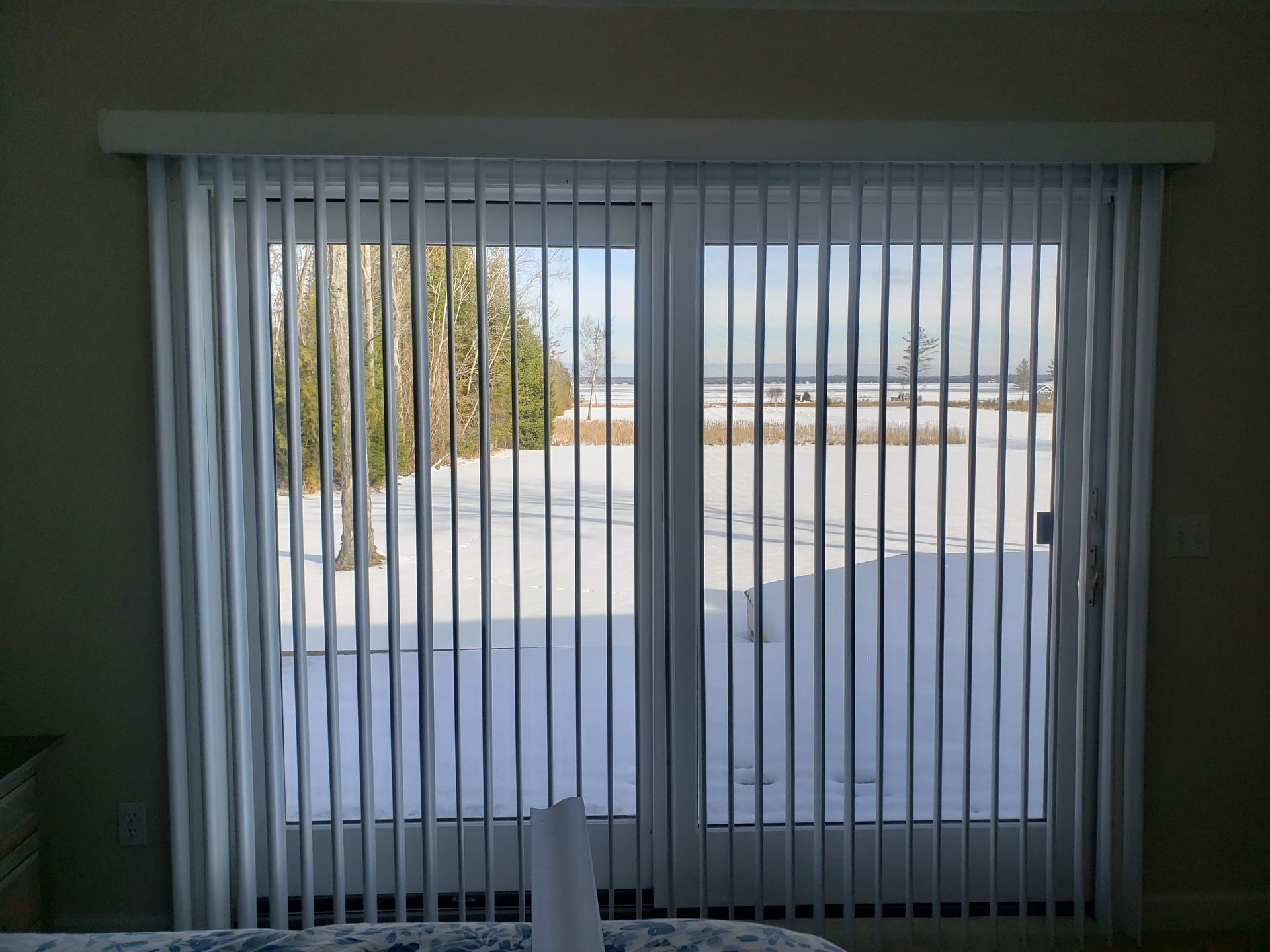 Vertical blinds covering a large window with a snowy outdoor view