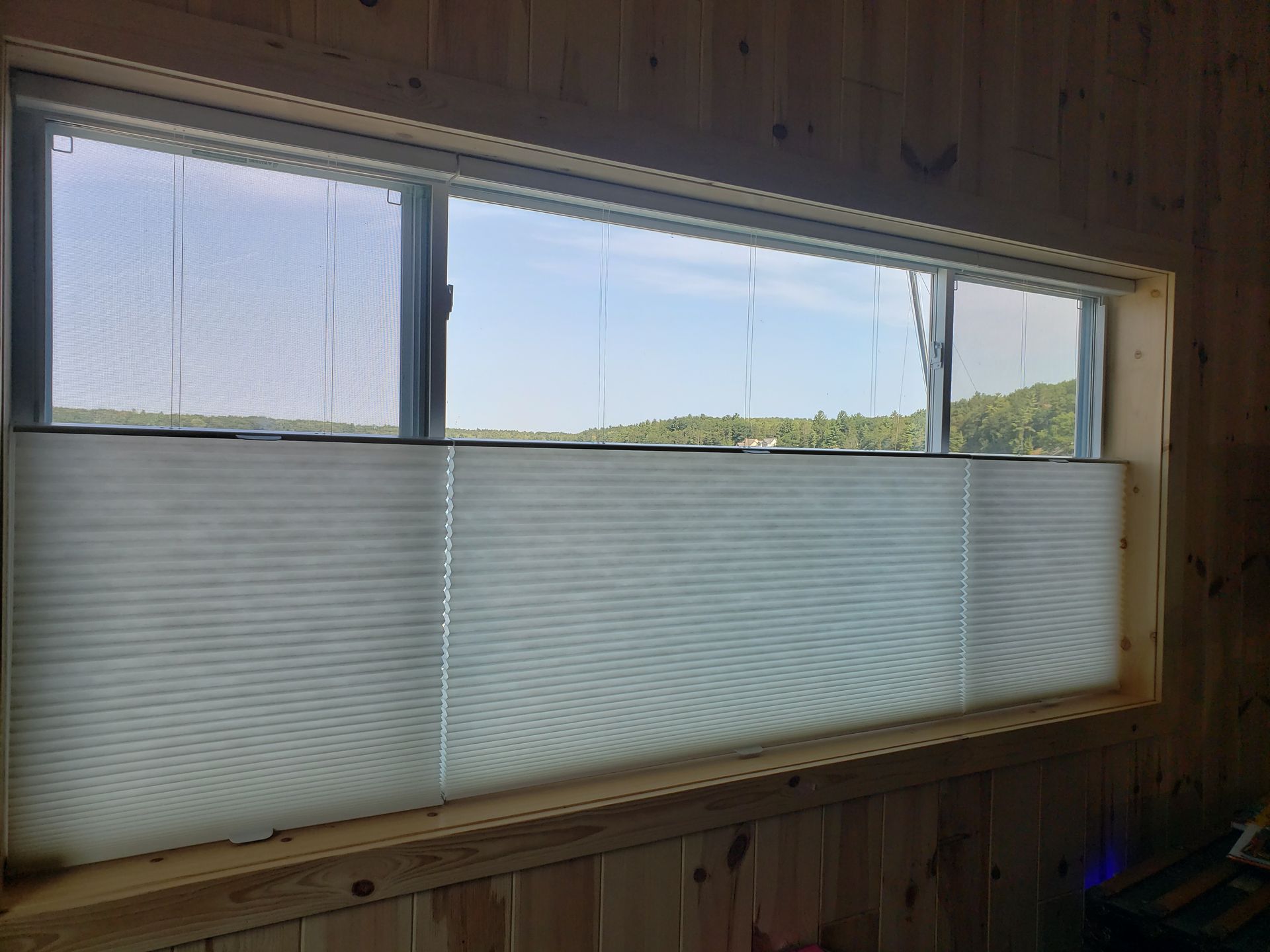 Small window with frosted lower panes in a wooden room, looking out to a grassy landscape.