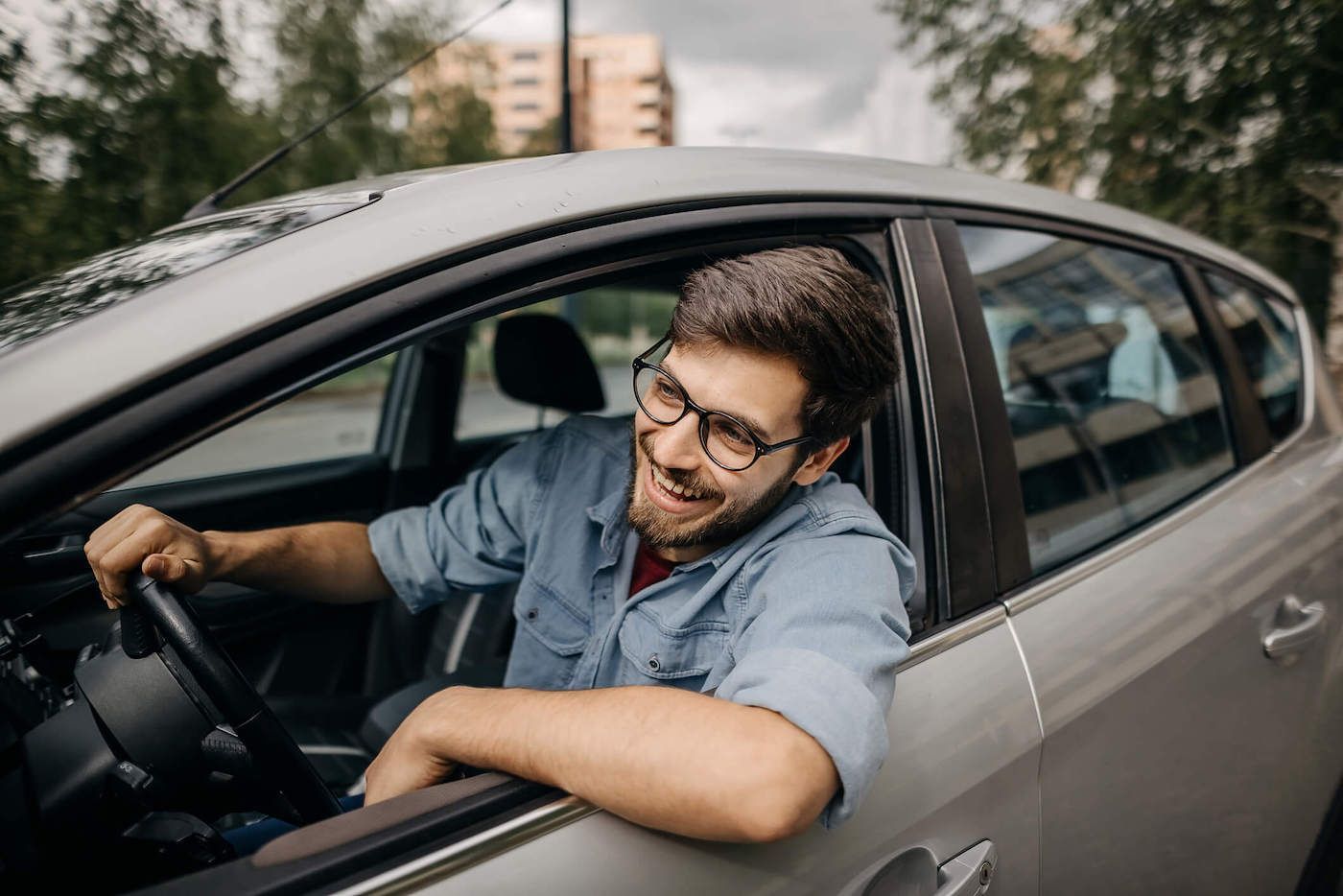a young man smiles while looking out his car window