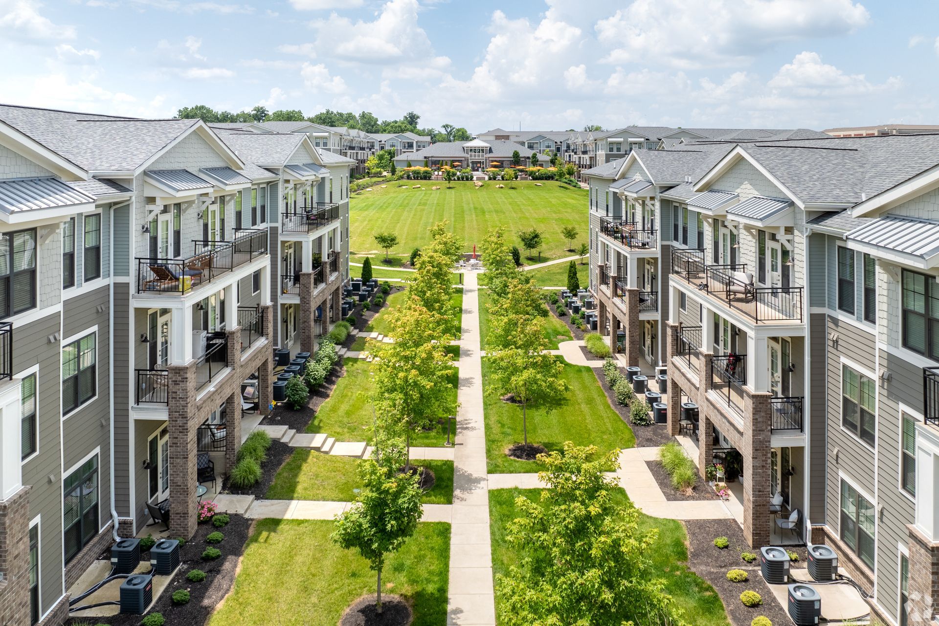 Aerial view of modern apartment buildings flanking a green courtyard with walkways and lawns