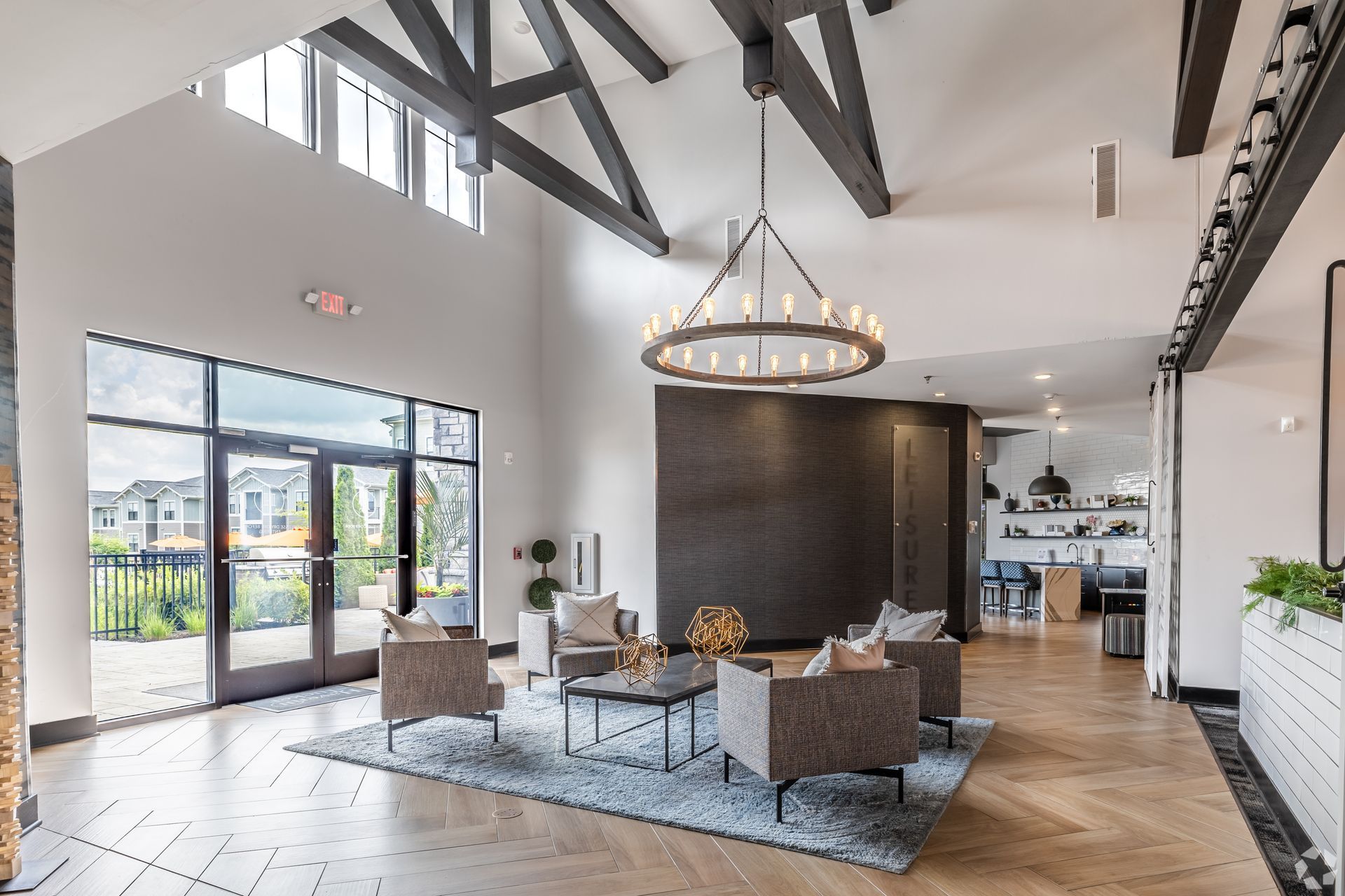Modern lobby seating area with high ceilings, glass doors, and a chandelier