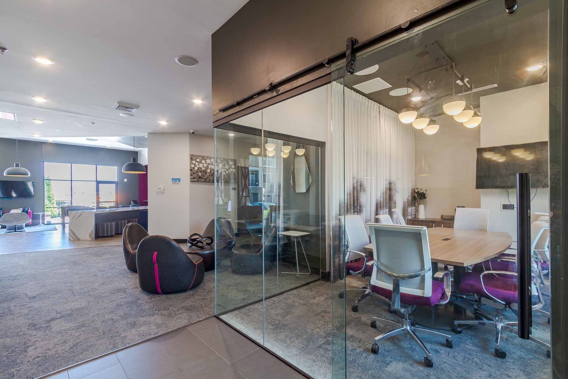Modern office space with a glass-walled conference room, lounge area, and a pool table at Haven on Tucker Apartments in Louisville, KY