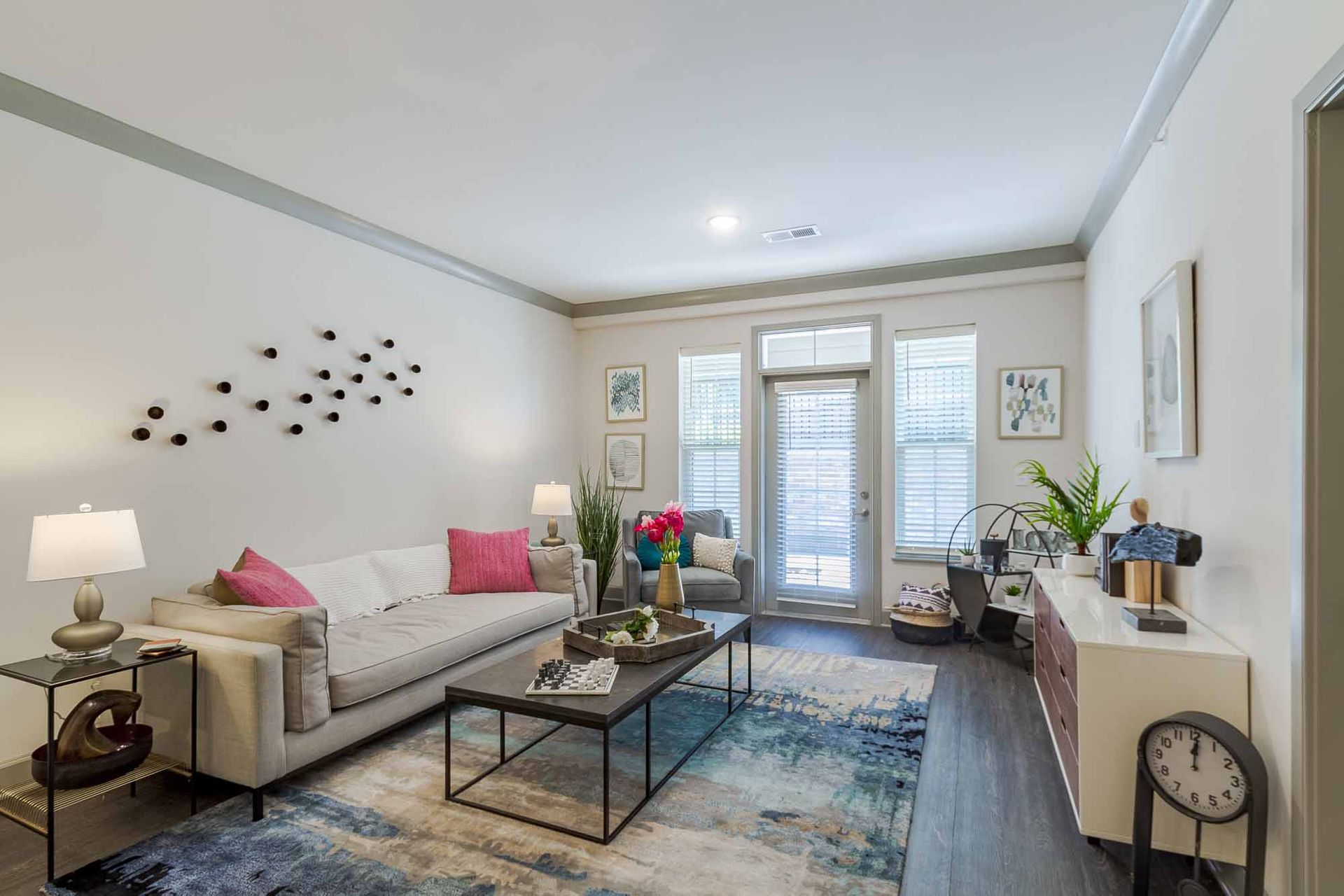 Living room with gray sofa, coffee table, rug, and balcony door at Haven on Tucker Apartments in Louisville, KY