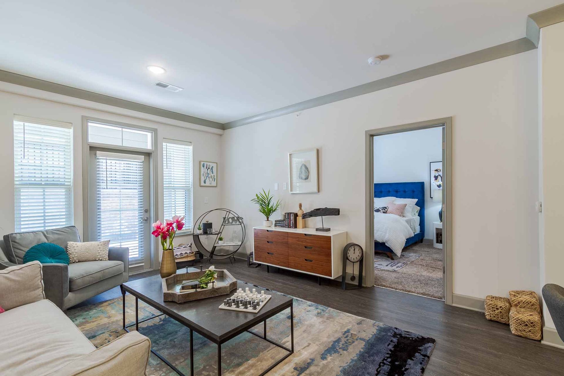 Living room with gray sofa, wooden cabinet, and view of a bedroom at Haven on Tucker Apartments in Louisville, KY