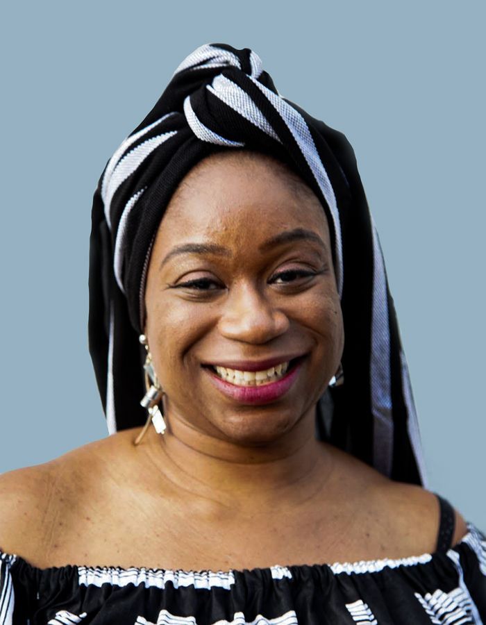 A woman wearing a turban is smiling for the camera