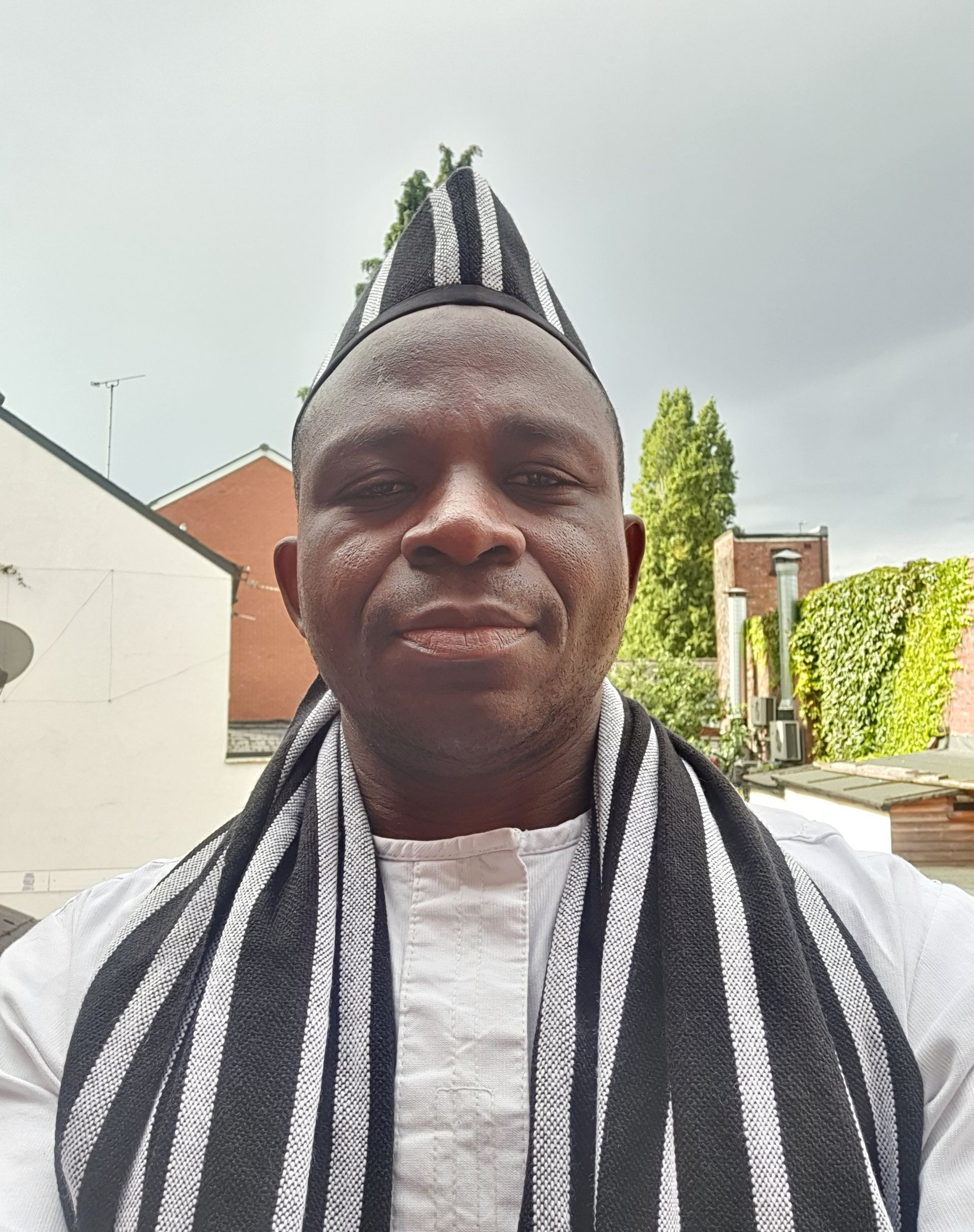 A man wearing a hat and scarf looks at the camera