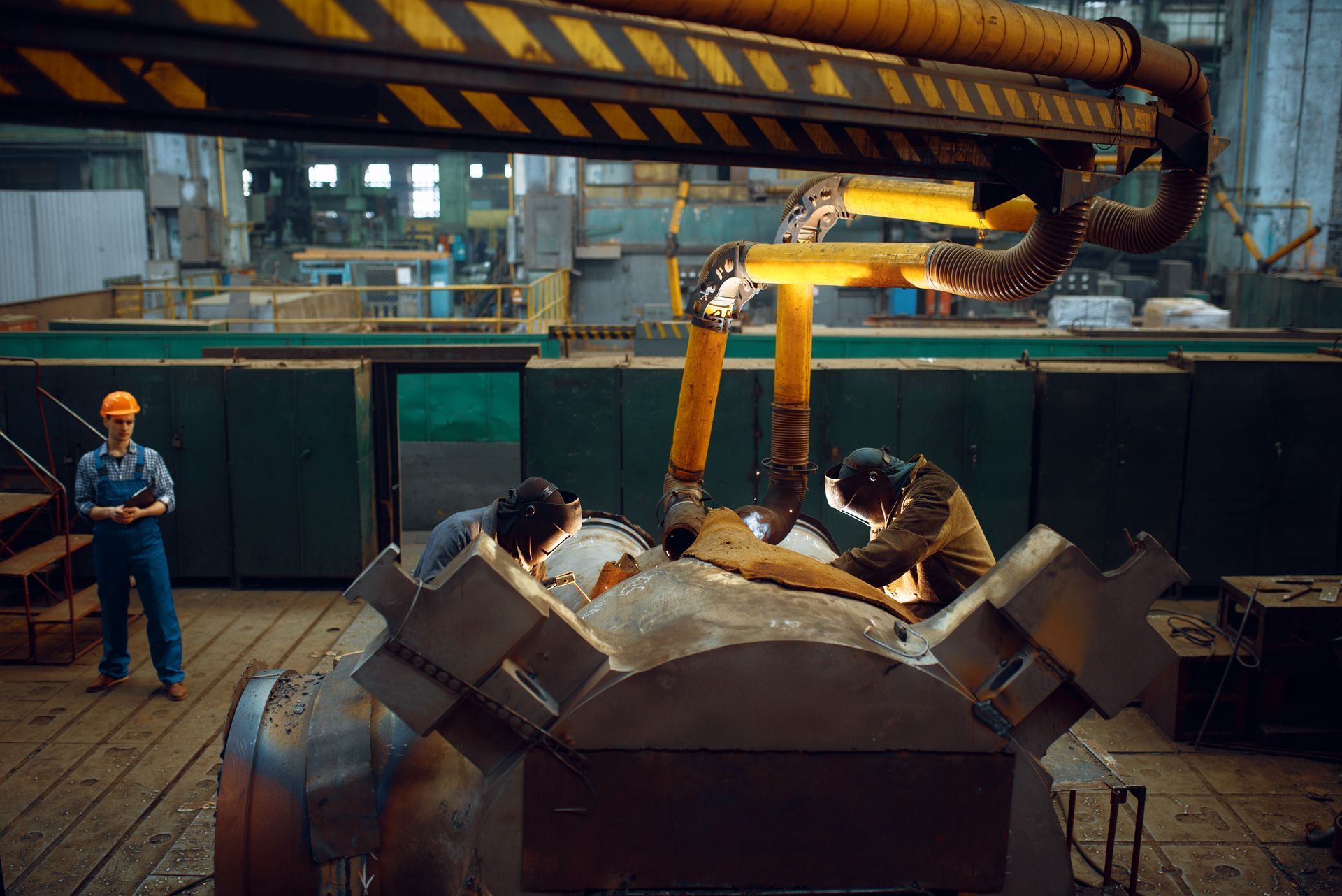 Workers operating a molten metal pouring machine in an industrial foundry