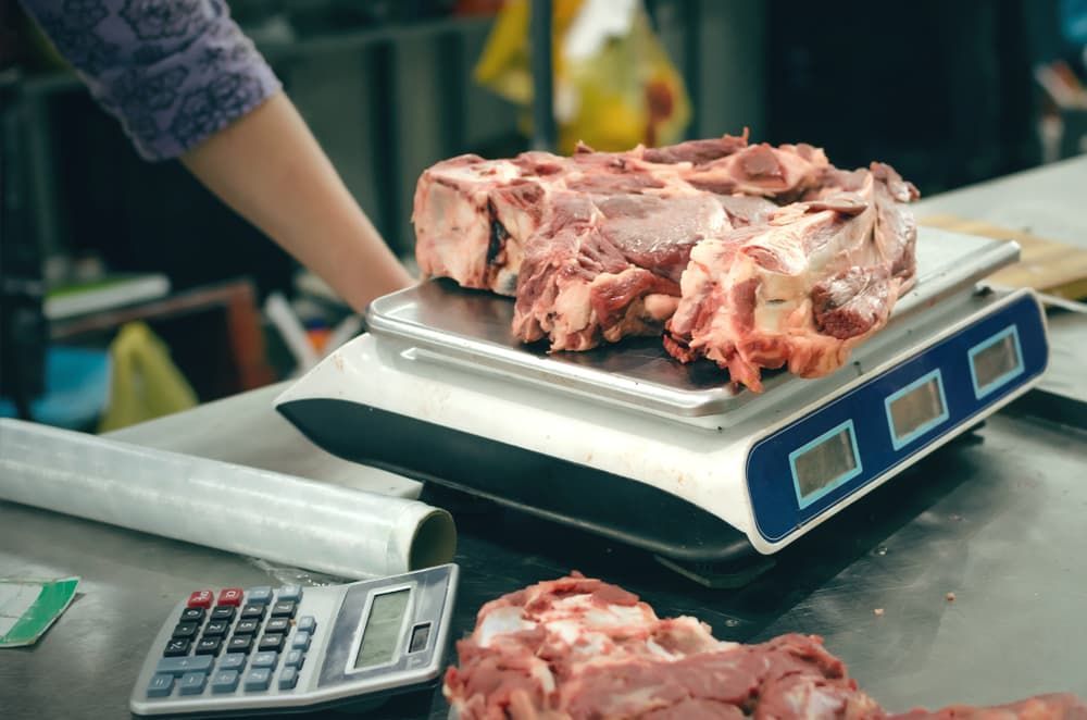 A Person Is Weighing a Large Piece of Meat on A Scale — Prime Meats NT in Coconut Grove, NT