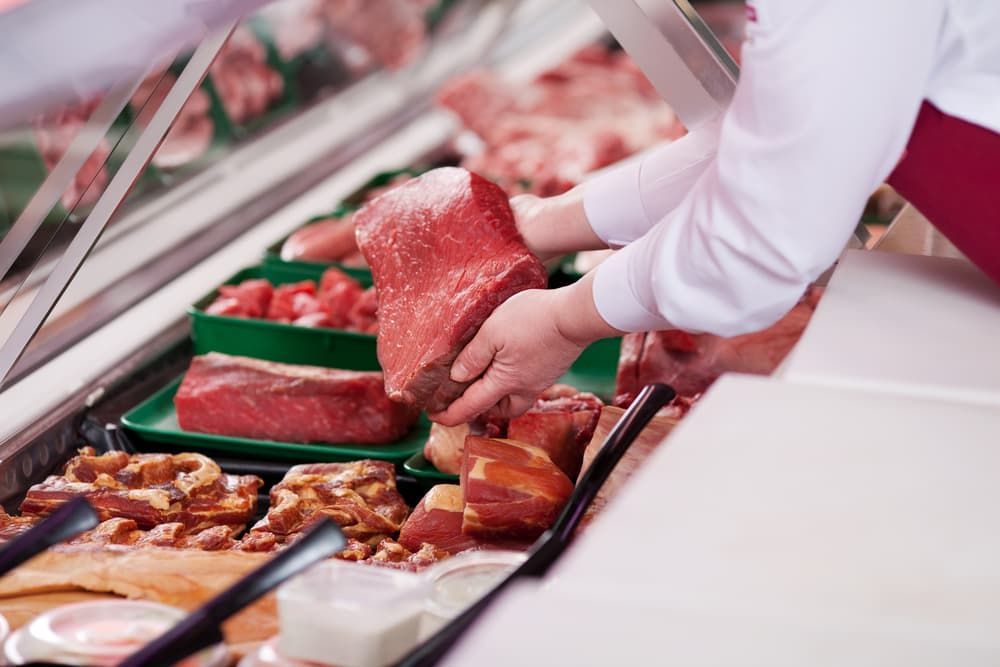 A Person Is Holding a Piece of Meat in A Butcher Shop — Prime Meats NT in Coconut Grove, NT
