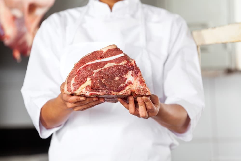 A Butcher Is Holding a Large Piece of Raw Meat in His Hands — Prime Meats NT in Coconut Grove, NT