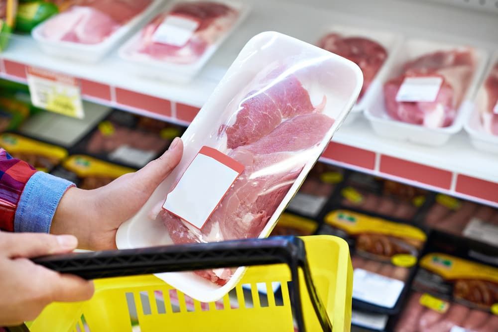 A Person Is Holding a Tray of Meat in A Grocery Store — Prime Meats NT in Coconut Grove, NT