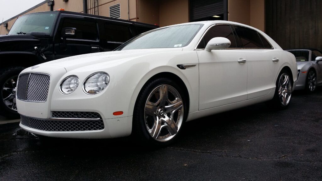 A white bentley is parked in front of a building