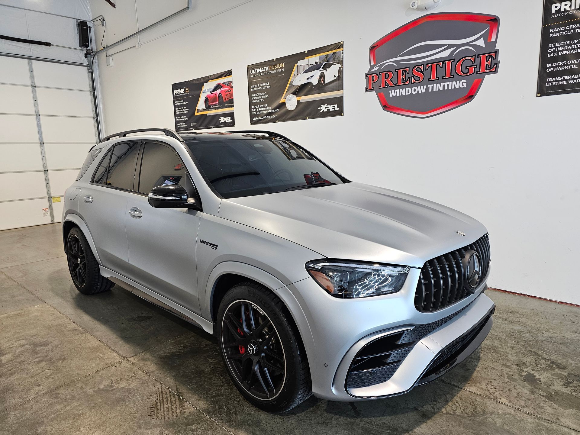 Silver Mercedes SUV in a garage showroom, angled front view with black rims and red brake calipers.