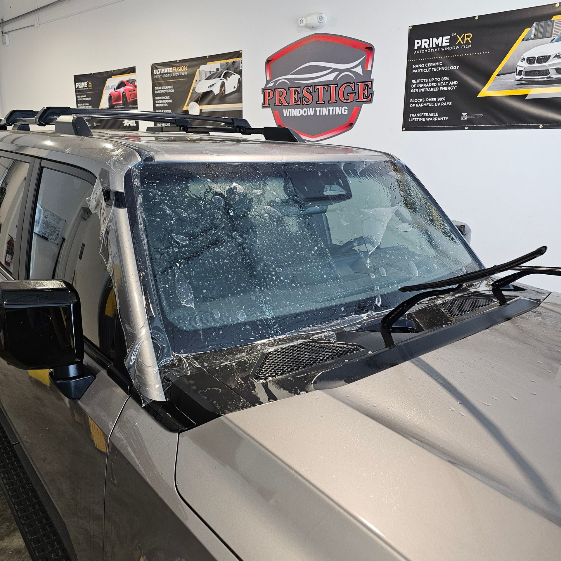 Silver SUV with windshield covered in shattered glass inside a dealership showroom