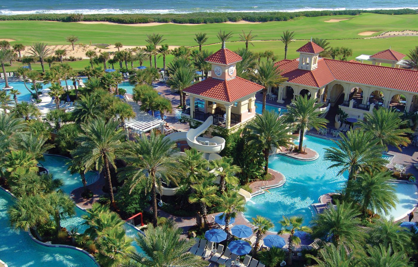 An aerial view of a large swimming pool surrounded by palm trees.
