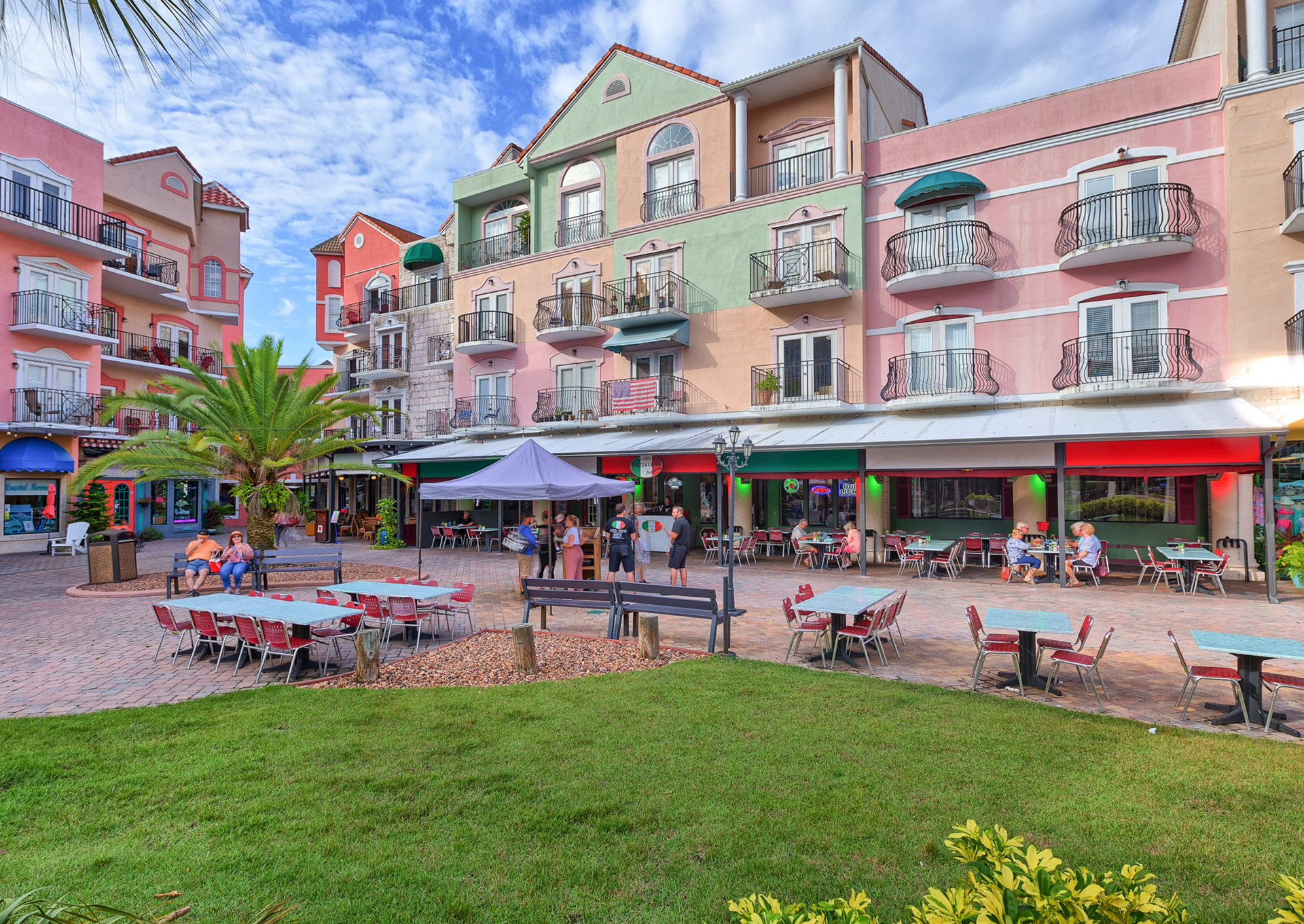 A row of buildings with tables and chairs in front of them.