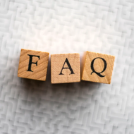 Wooden blocks spelling “FAQ” on a textured white background