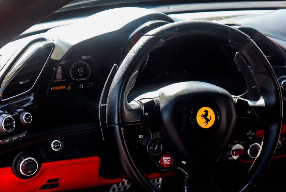 Ferrari steering wheel and dashboard interior with red accents in a sports car