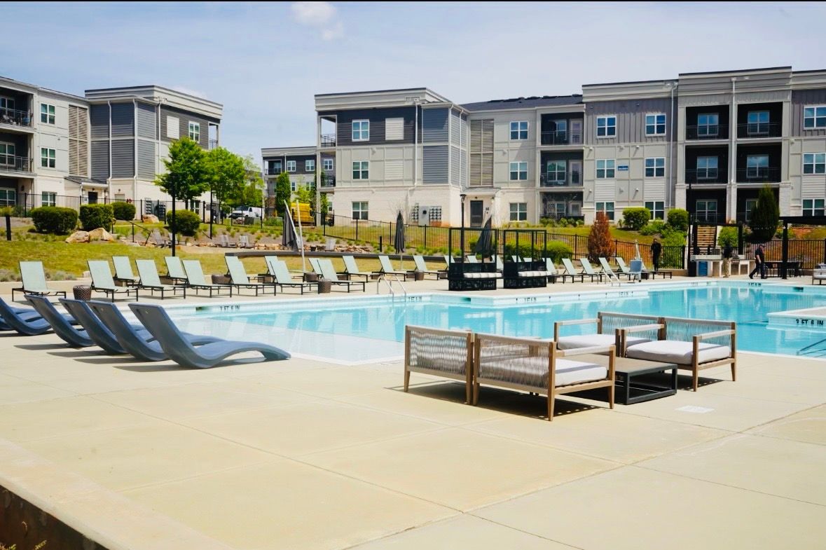 Apartment pool with lounge chairs and seating area on a sunny day