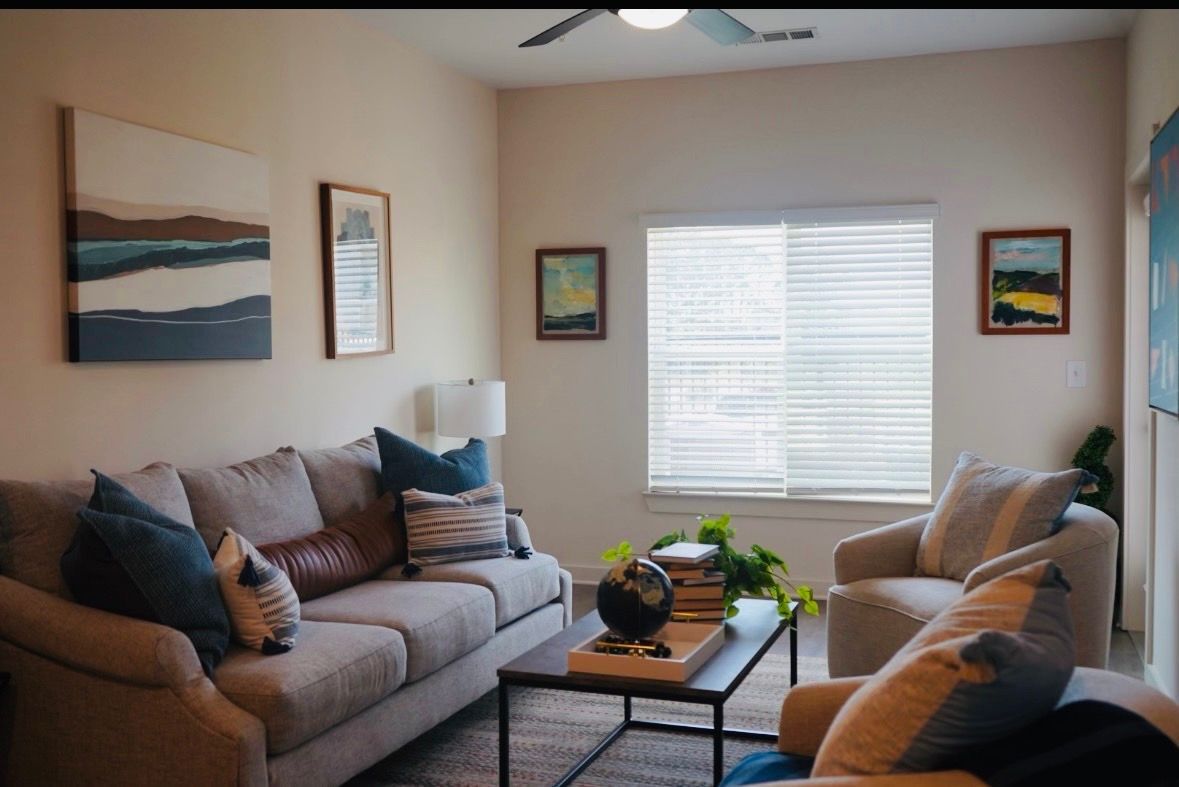 Cozy living room with two sofas, coffee table, wall art, and a window with blinds.