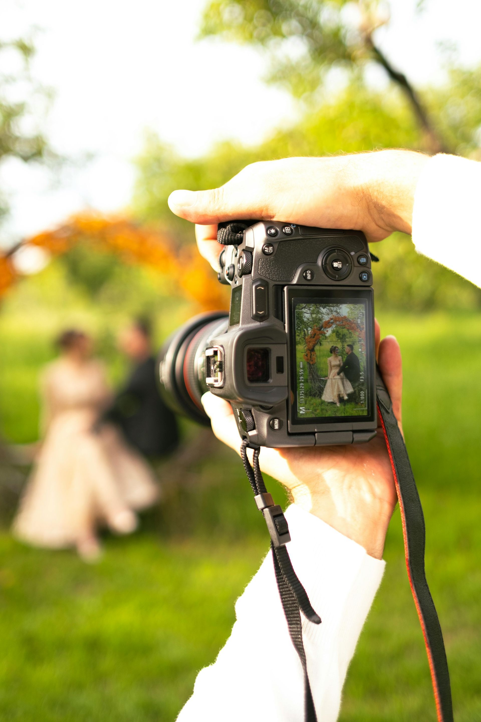 Camera held up to photograph a blurred couple outdoors in a green park
