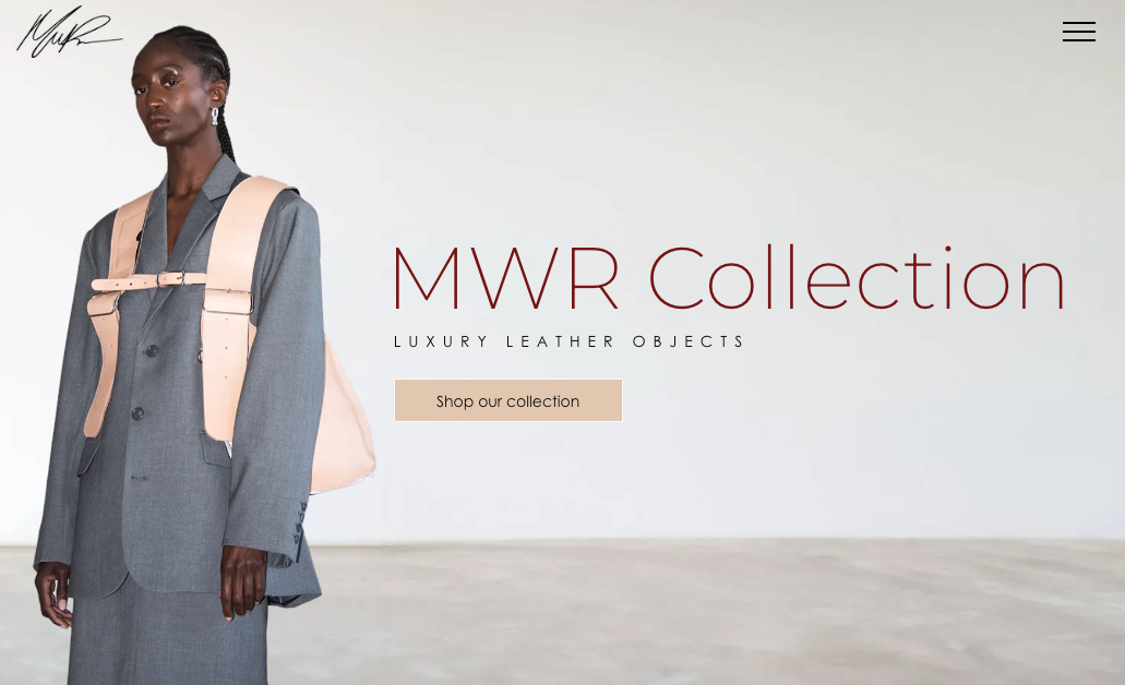 MWR Collection's new homepage design. A model wearing a grey blazer with a naked body luggage over a neutral backdrop.