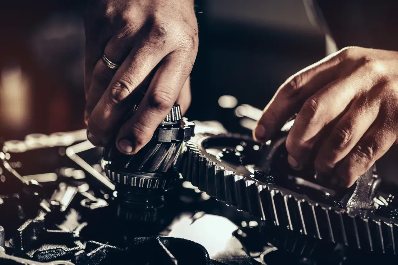 Hands assembling gears, close-up, working on machinery.