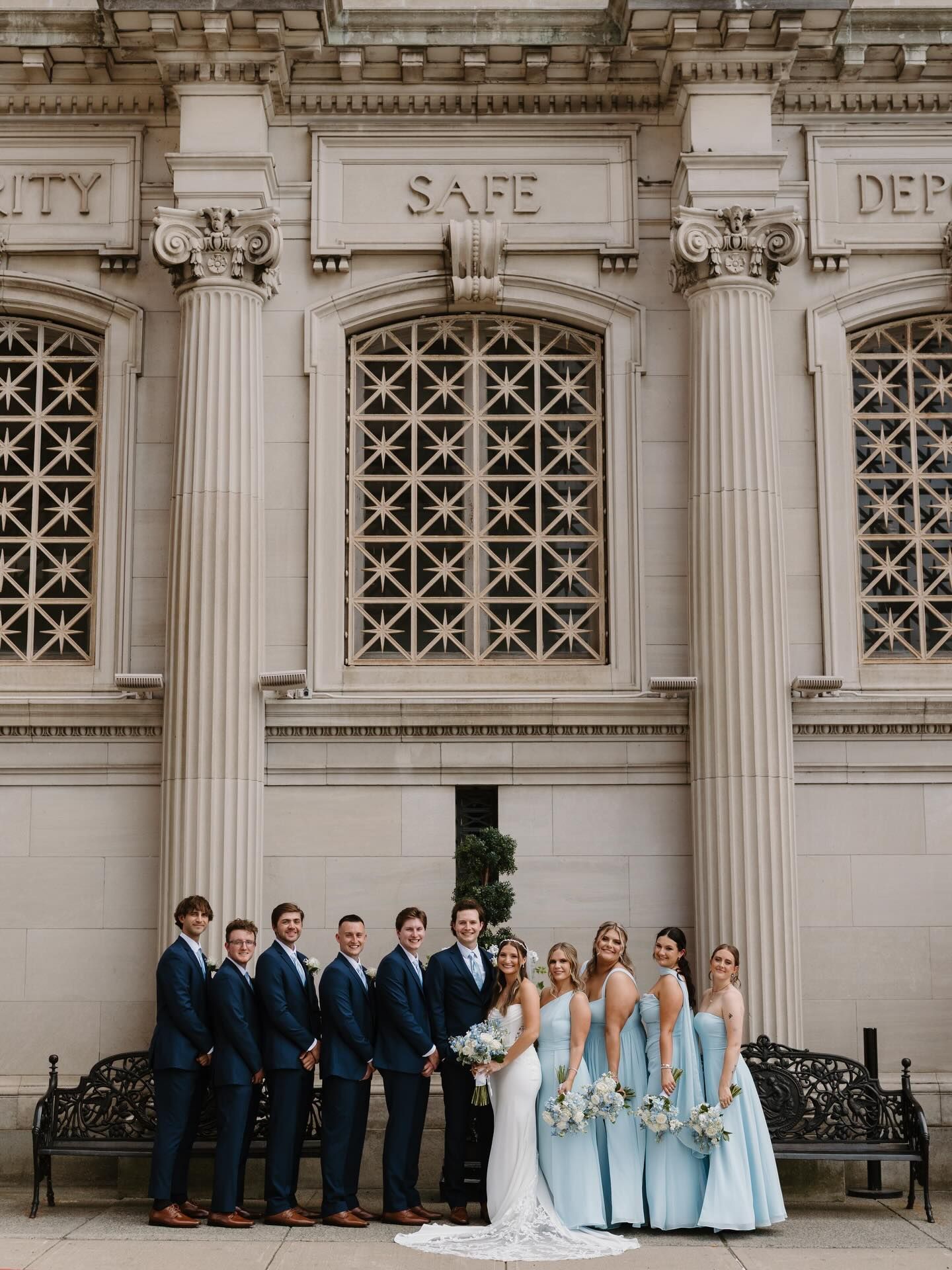 Wedding party posing outside a grand stone building with columns and arched windows