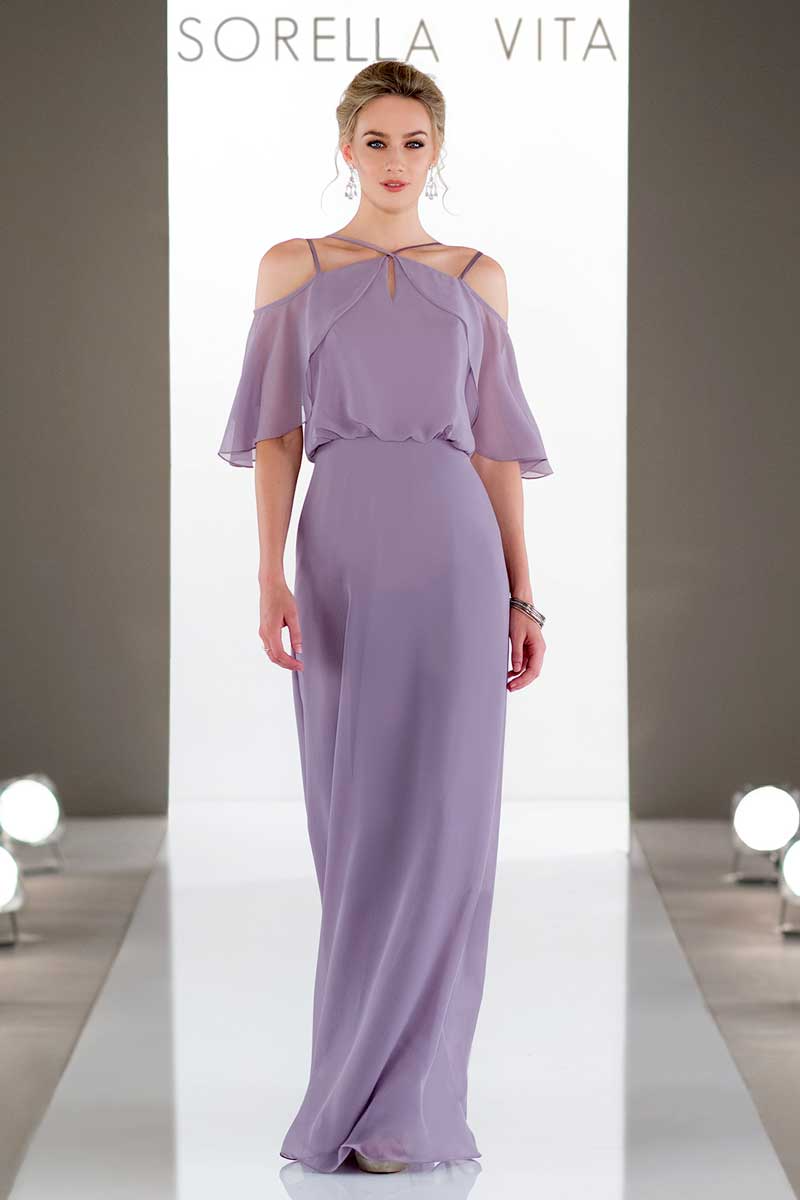 Model in a lavender gown walking a runway beneath the Sorella Vita sign.