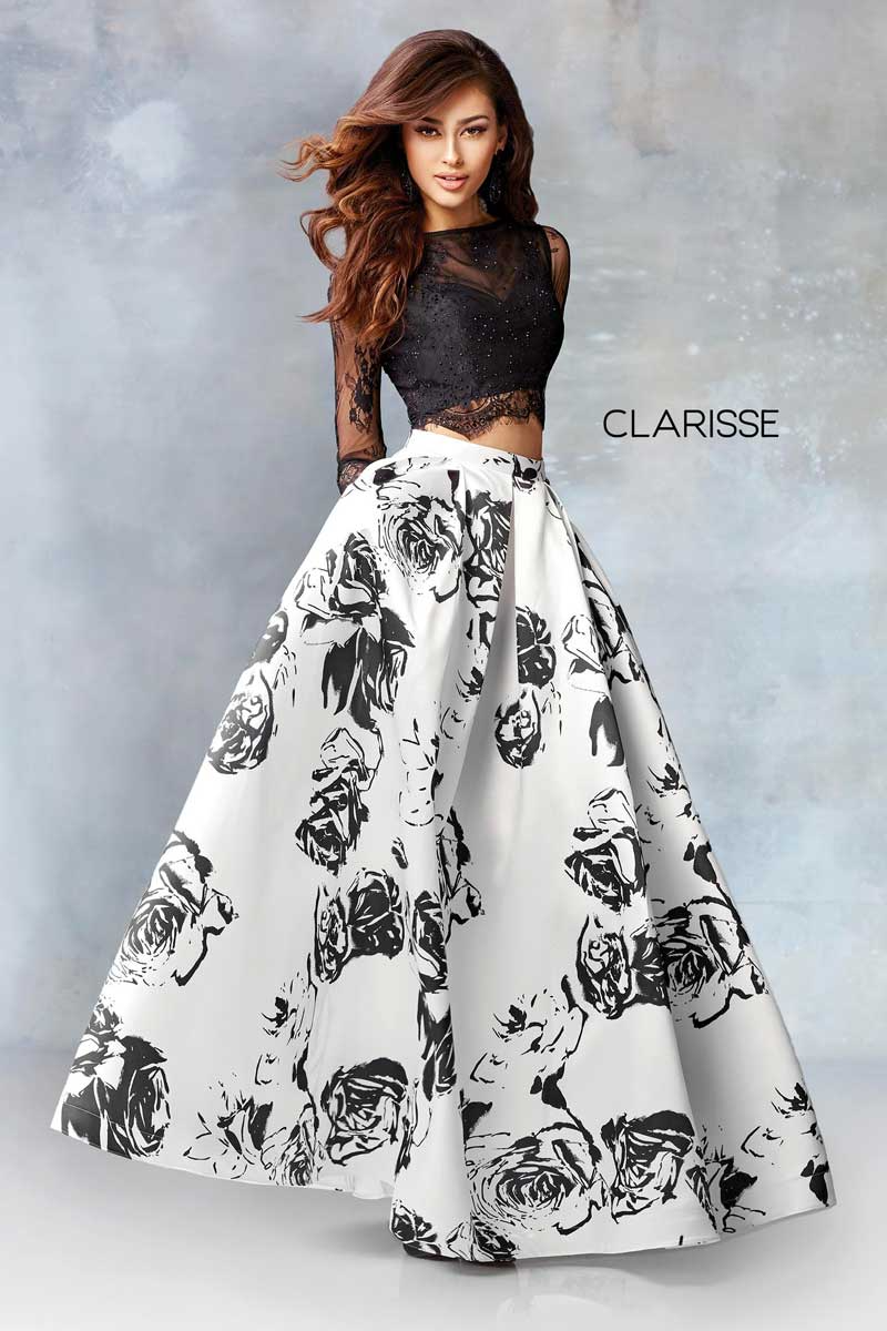 Woman in a black lace top and white floral ball gown, standing against a gray studio backdrop.