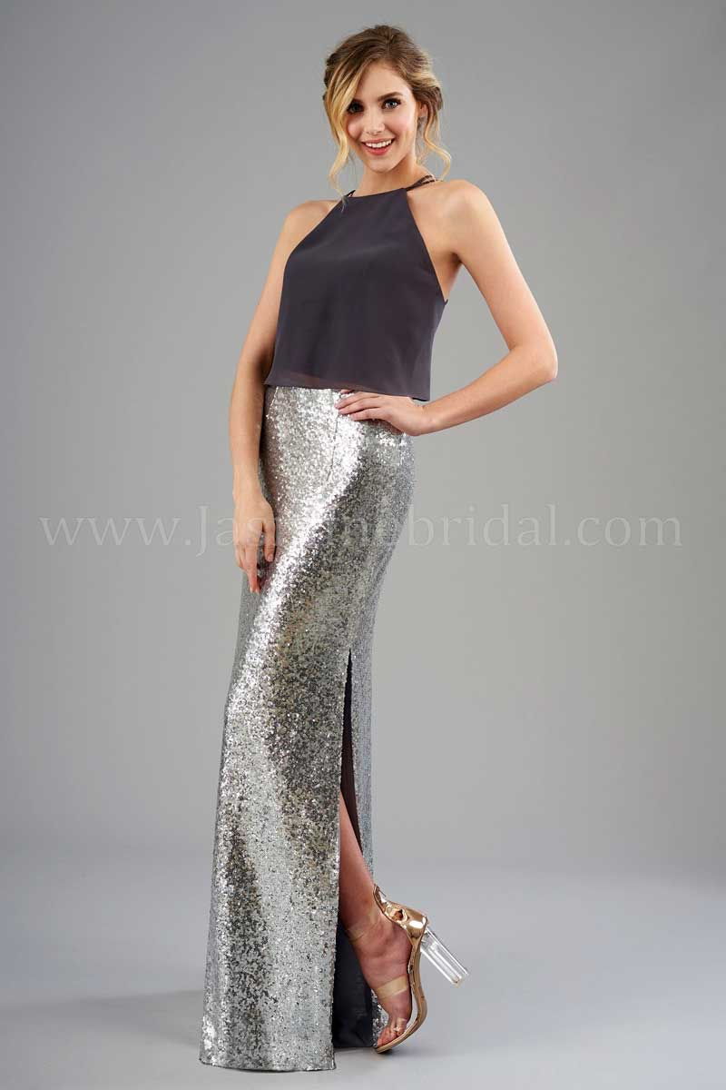 Woman in a dark sleeveless top and silver sequined skirt posing against a gray backdrop.