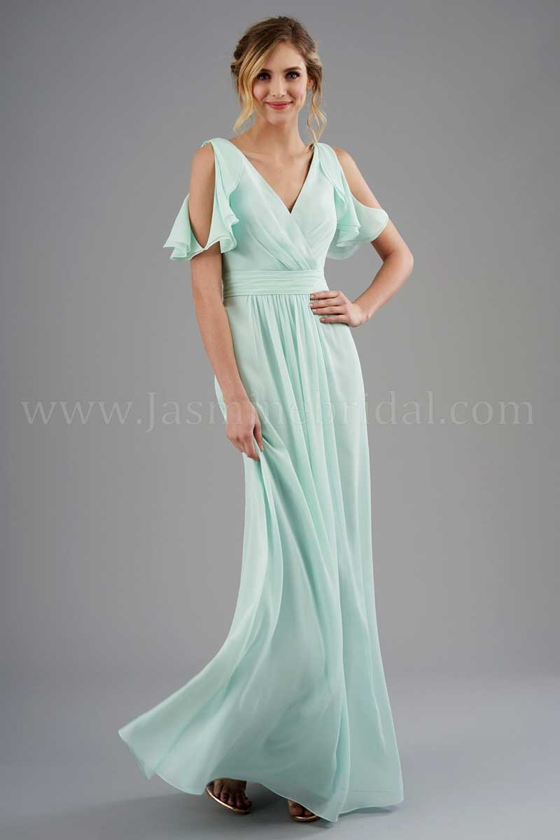 Woman in a mint green flowing dress posing against a gray studio backdrop