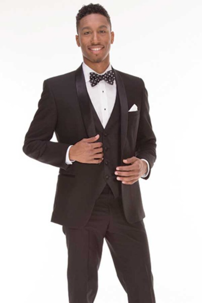 Man in a black tuxedo with bow tie, standing and smiling against a white background