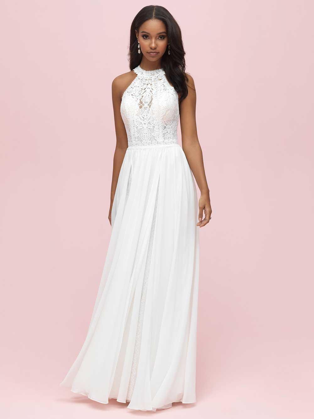Woman in a white halter gown standing against a pink background.
