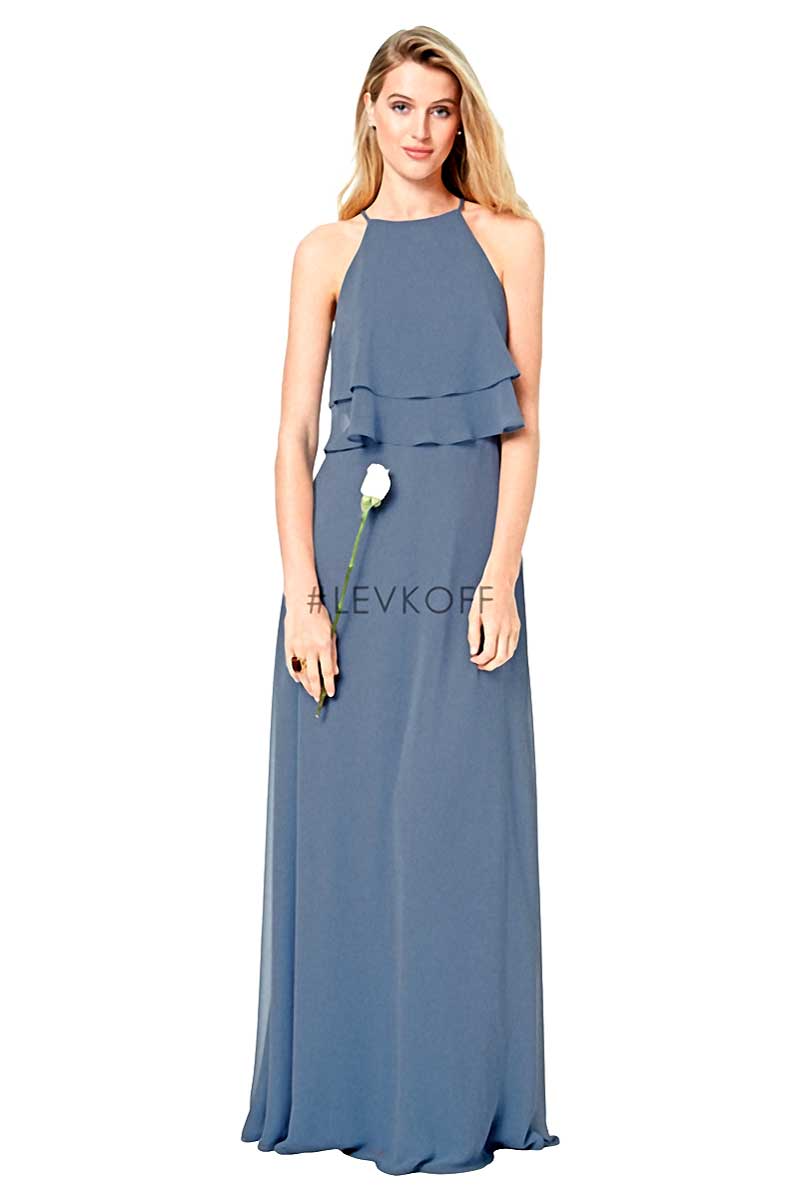 Woman in a blue halter maxi dress with a layered neckline, standing against a white background