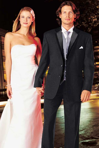 A woman in a white gown and a man in a dark suit pose together at a formal evening event.