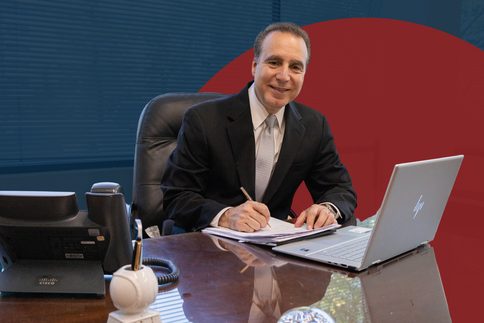 A man in a suit is sitting at a desk with a laptop.