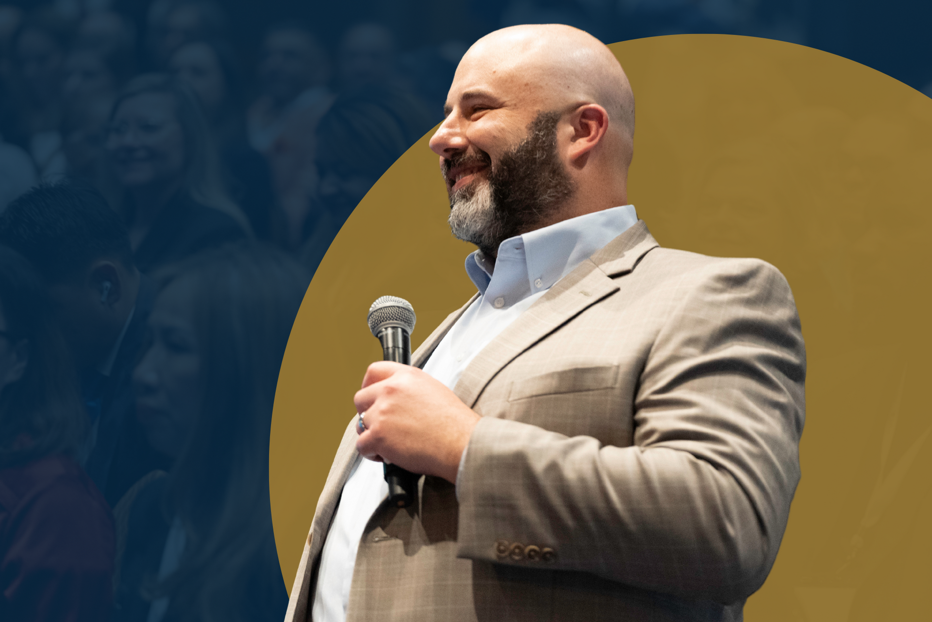 A man in a suit is holding a microphone in front of a crowd.