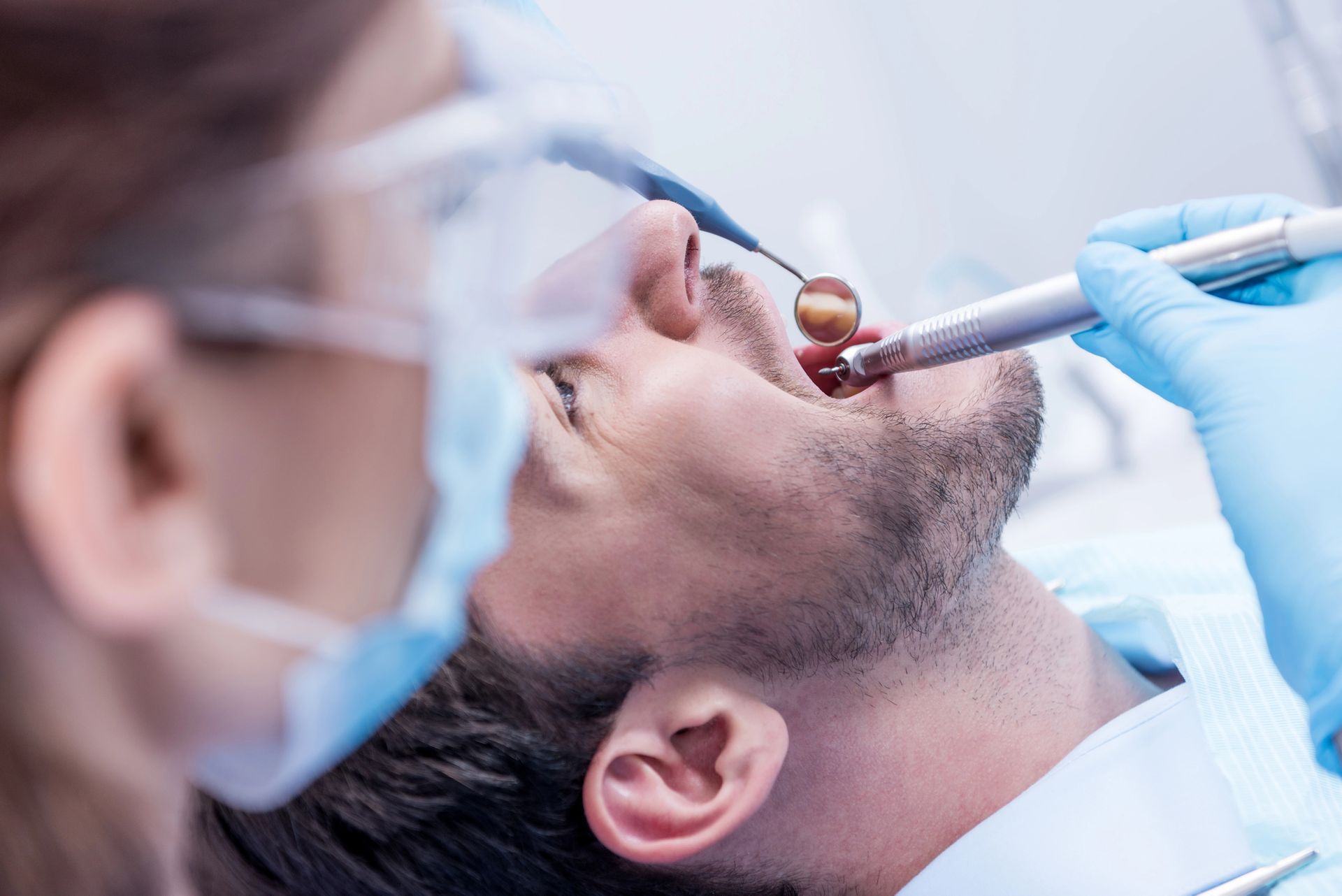 Dentista che esamina la bocca di un paziente con strumenti odontoiatrici e una mano guantata