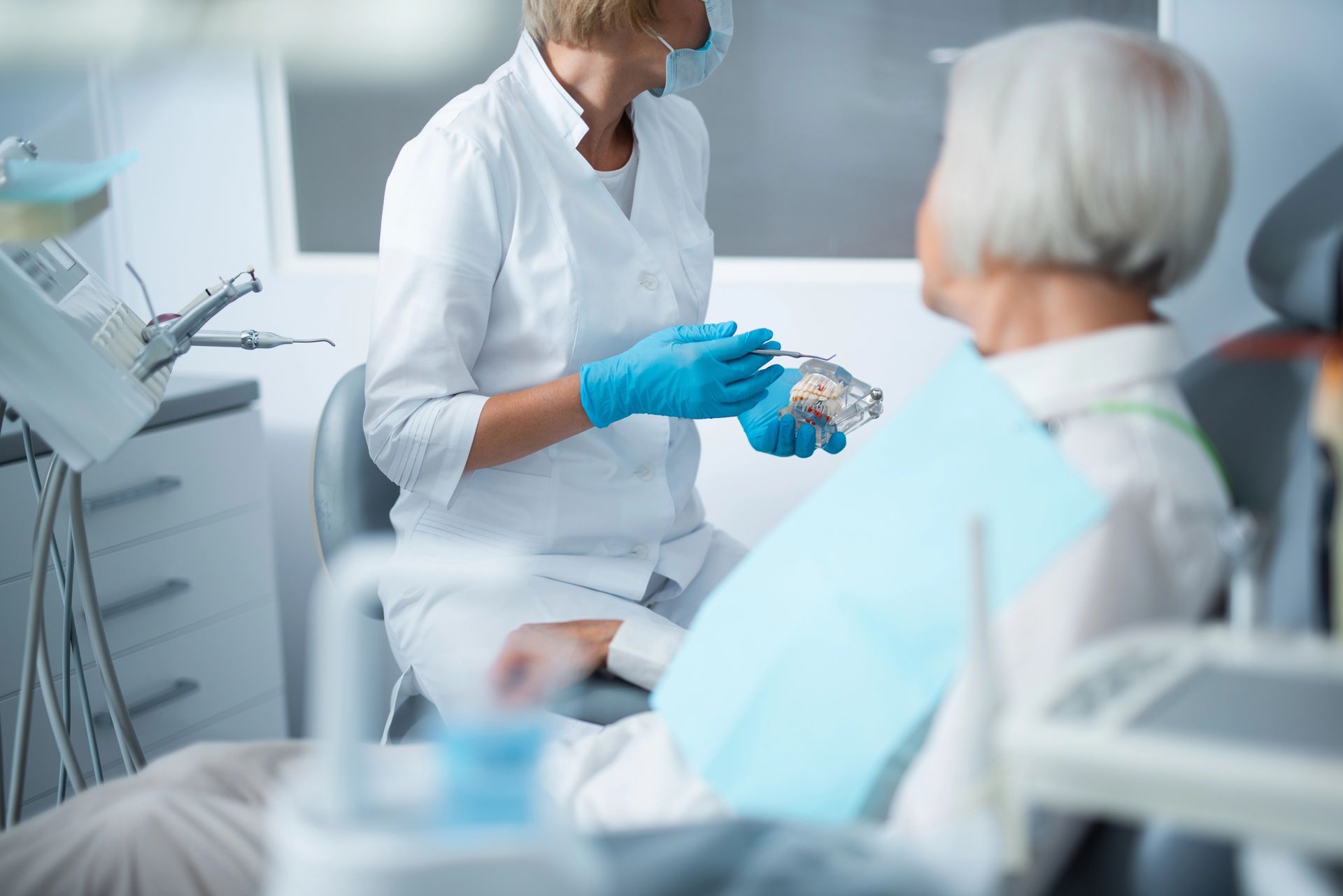 Operatore sanitario in camice bianco e guanti blu che parla con un paziente nell’area d’attesa di una clinica