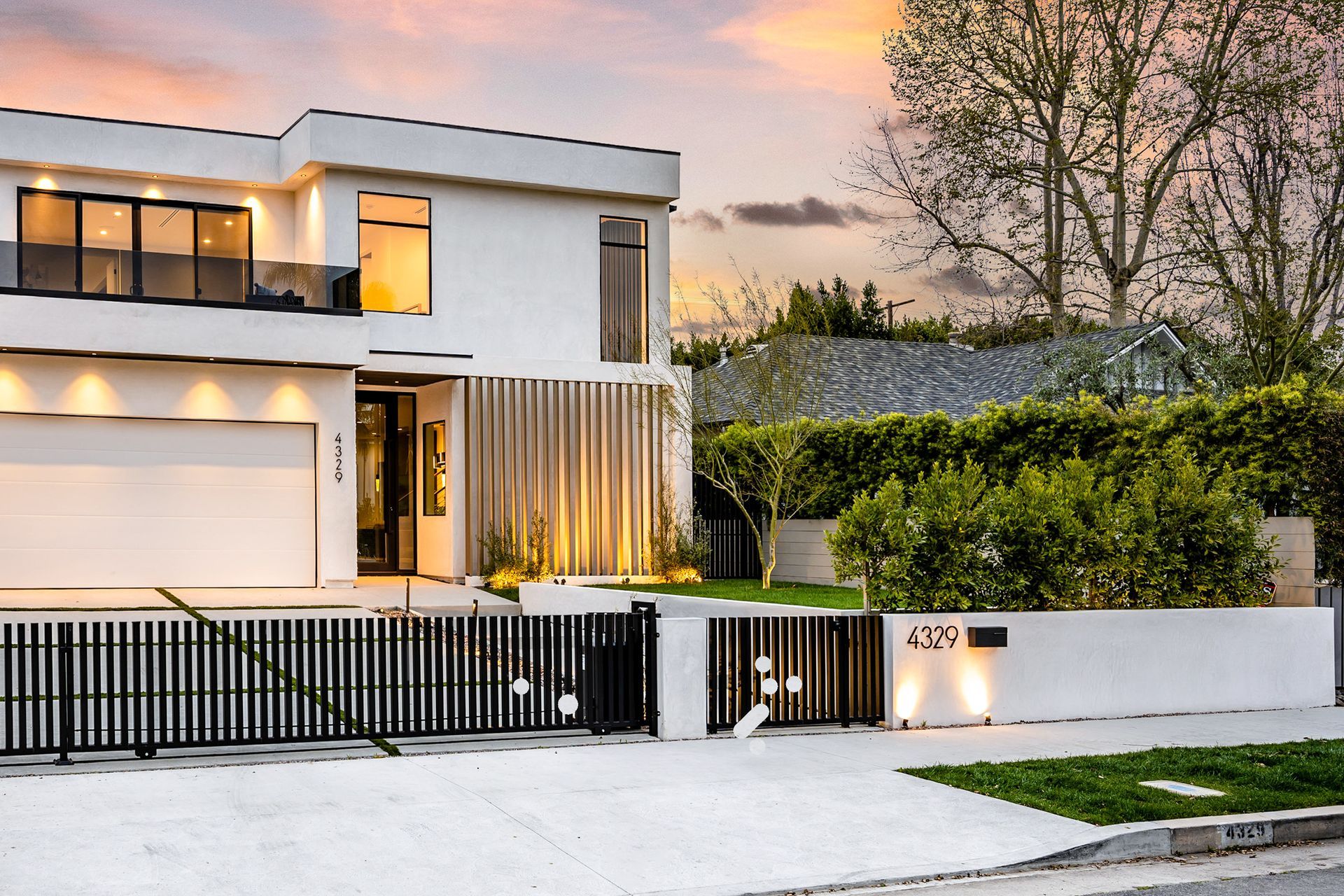 Modern white two-story house with black gate and driveway at sunset | Beth Ellinthorpe Realtor | Luxury Real Estate