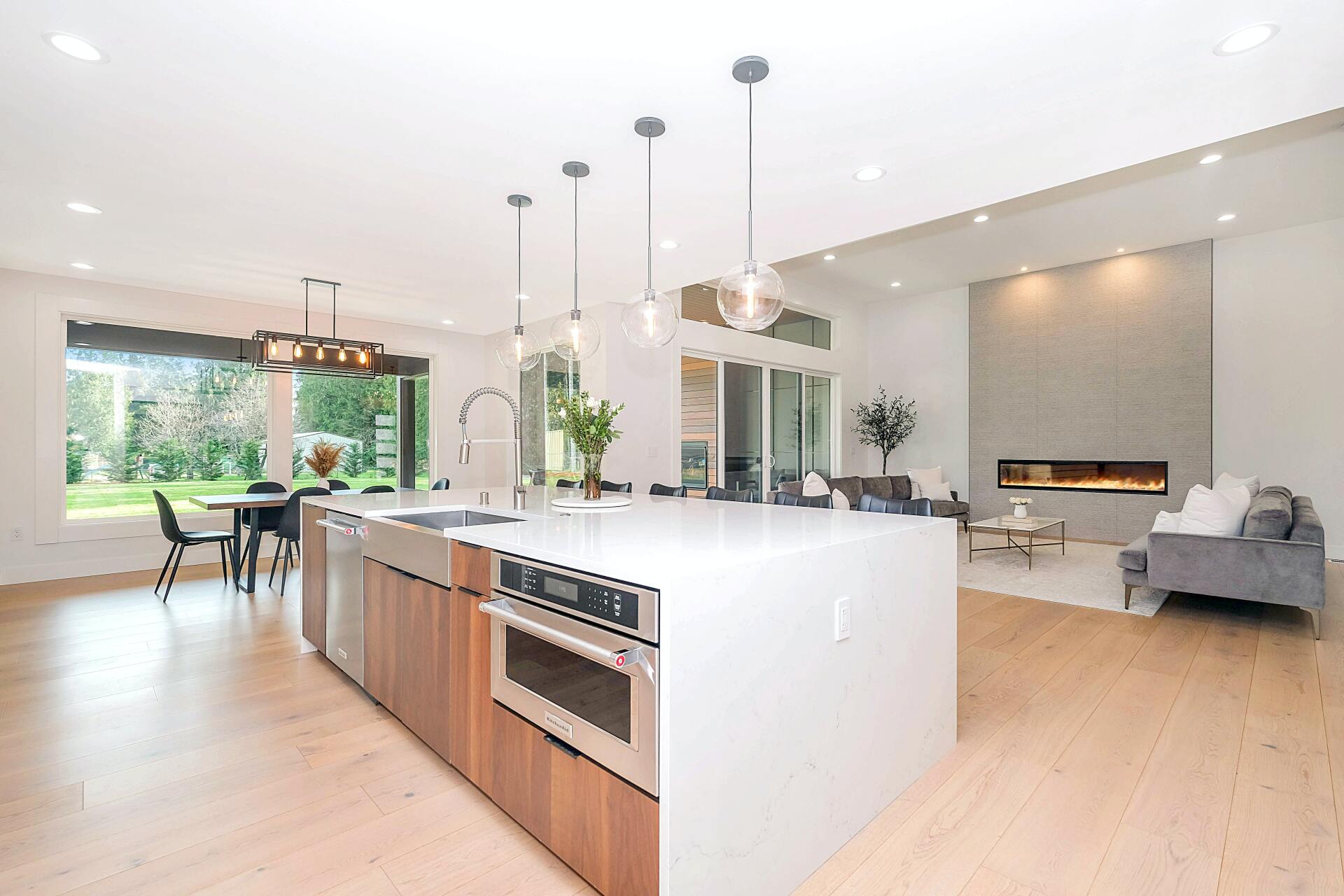 Bright open-plan kitchen and living room with white island, light wood floors, and large windows | Beth Ellinthorpe Realtor | Luxury Real Estate