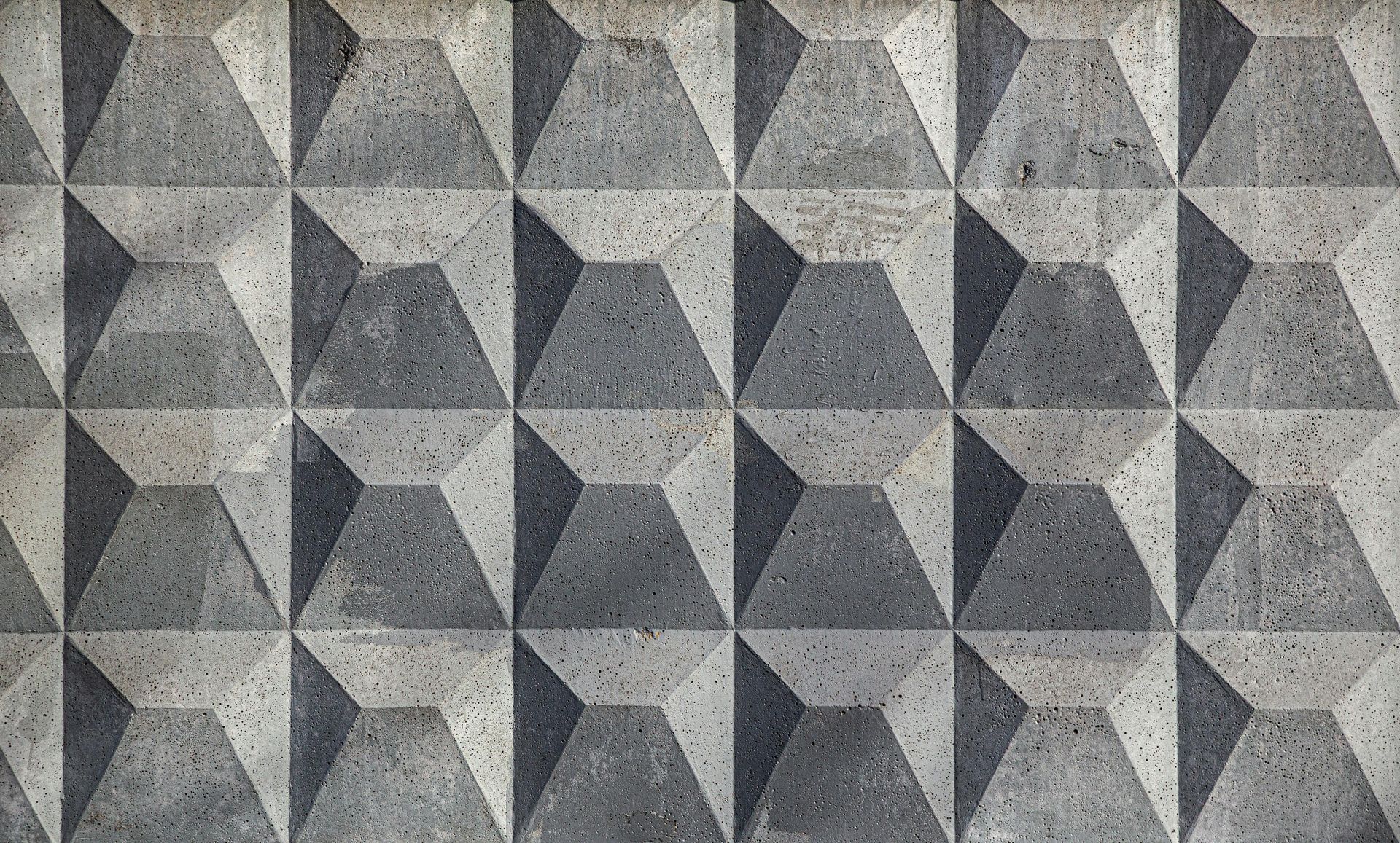 Concrete wall with repeating geometric pyramid shapes, shaded gray.